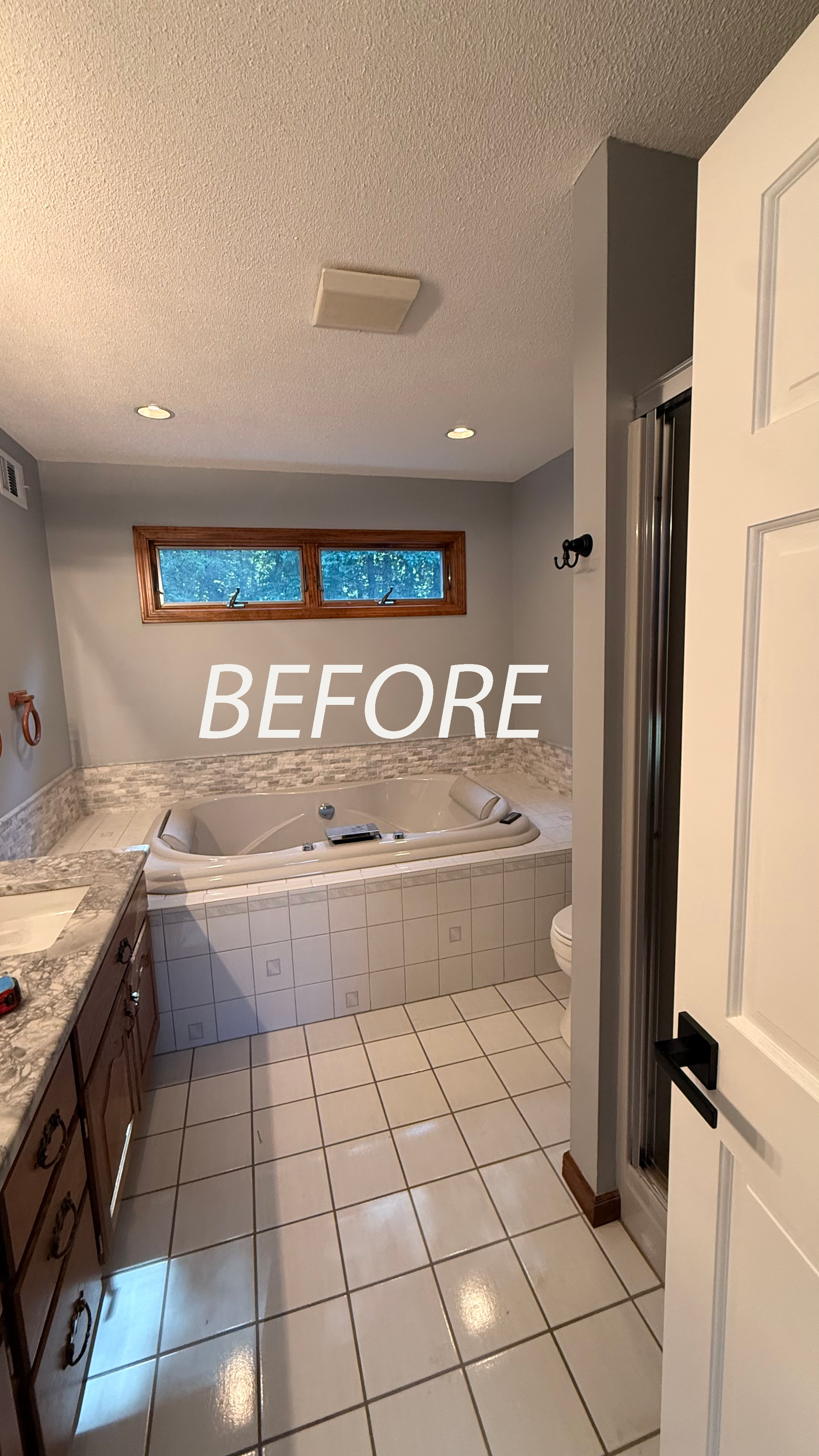 Before photo of a tiled bathroom in Rocky Hill, CT with a jetted tub, window, vanity, and open door.