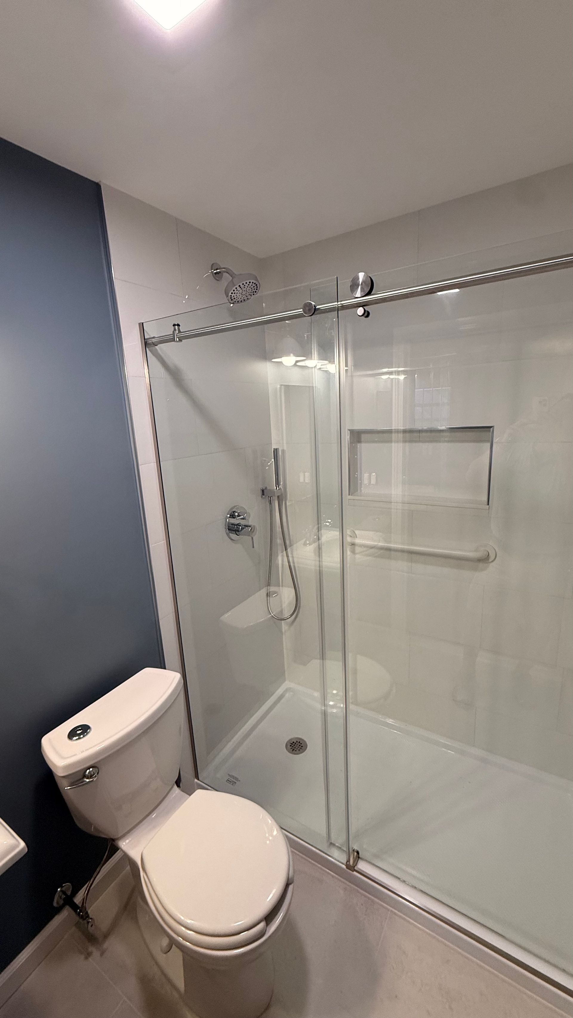 Modern bathroom with toilet, glass shower enclosure, and gray walls. By First Choice Bathroom Remodeling done in Avon, CT.