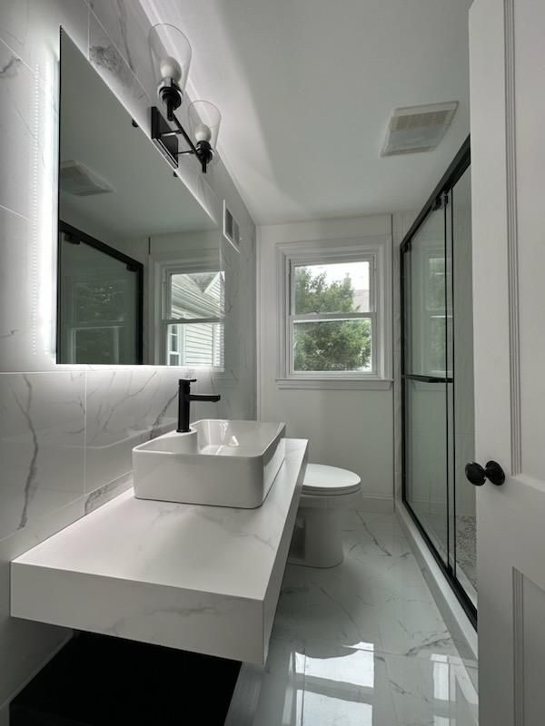 A bathroom with a sink , toilet and mirror.