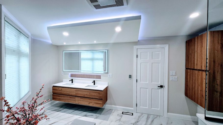 Modern bathroom remodel in Southington, CT with floating wood vanity, large mirror, white door, and marble tile flooring.
