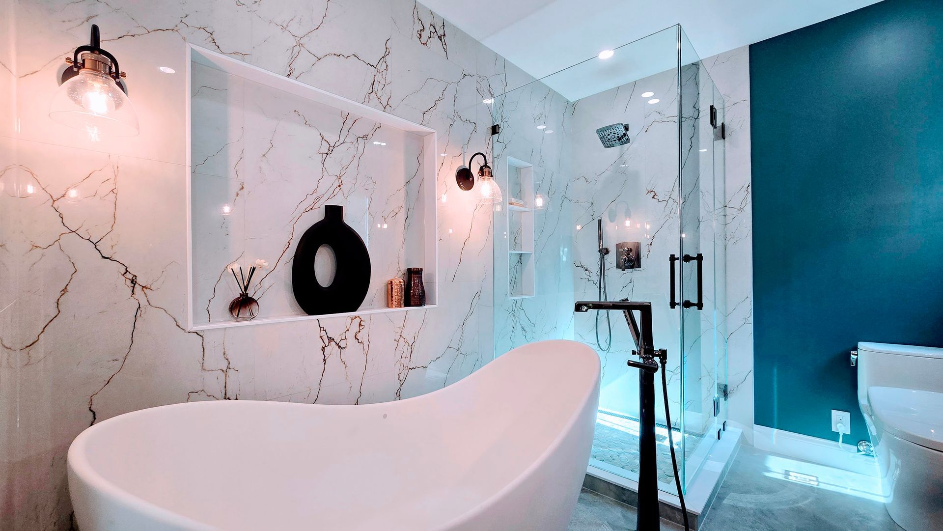 Modern bathroom with white bathtub, glass shower, teal wall, and marble-like tile.