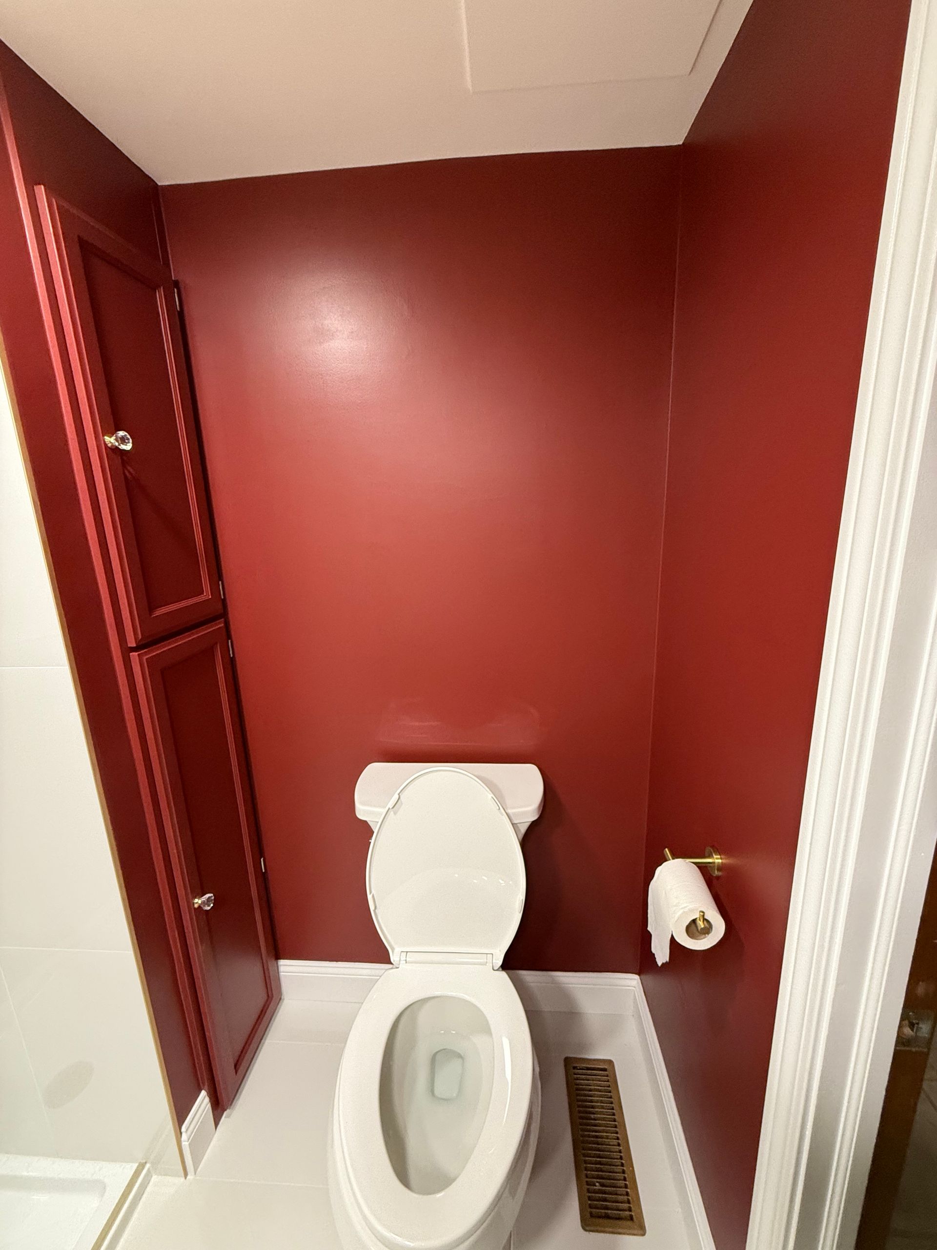 A toilet in a bathroom with red walls