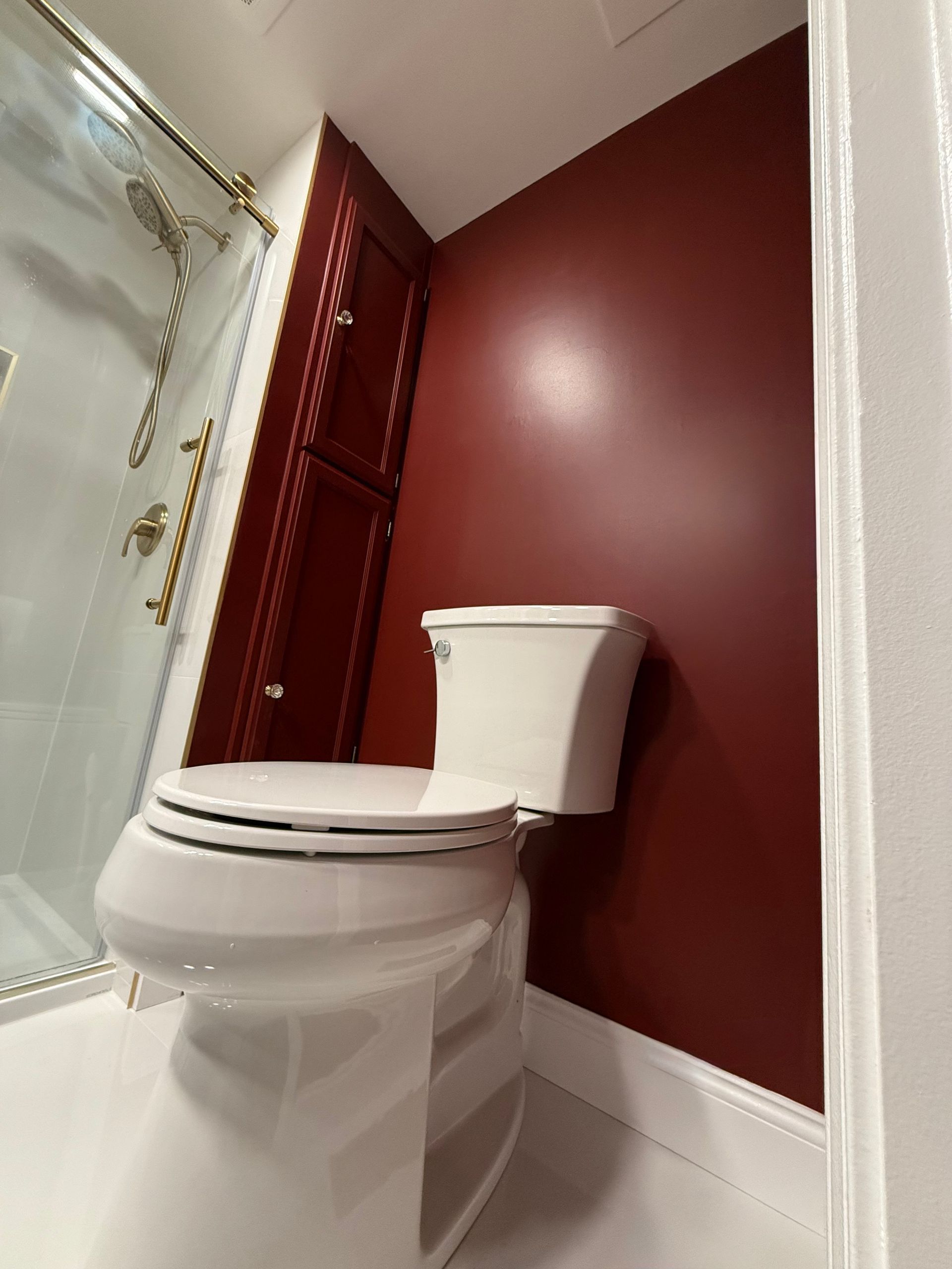 A toilet in a bathroom with red walls