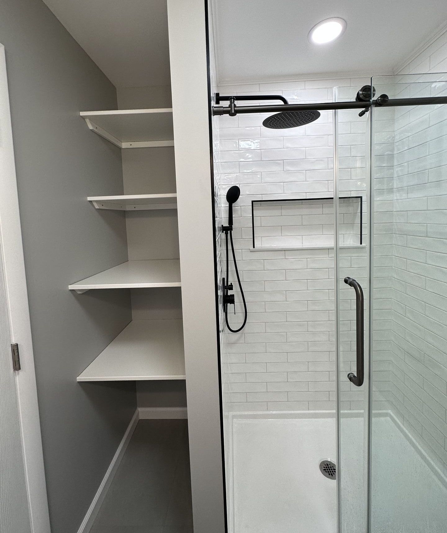 A bathroom with a walk in shower and shelves.