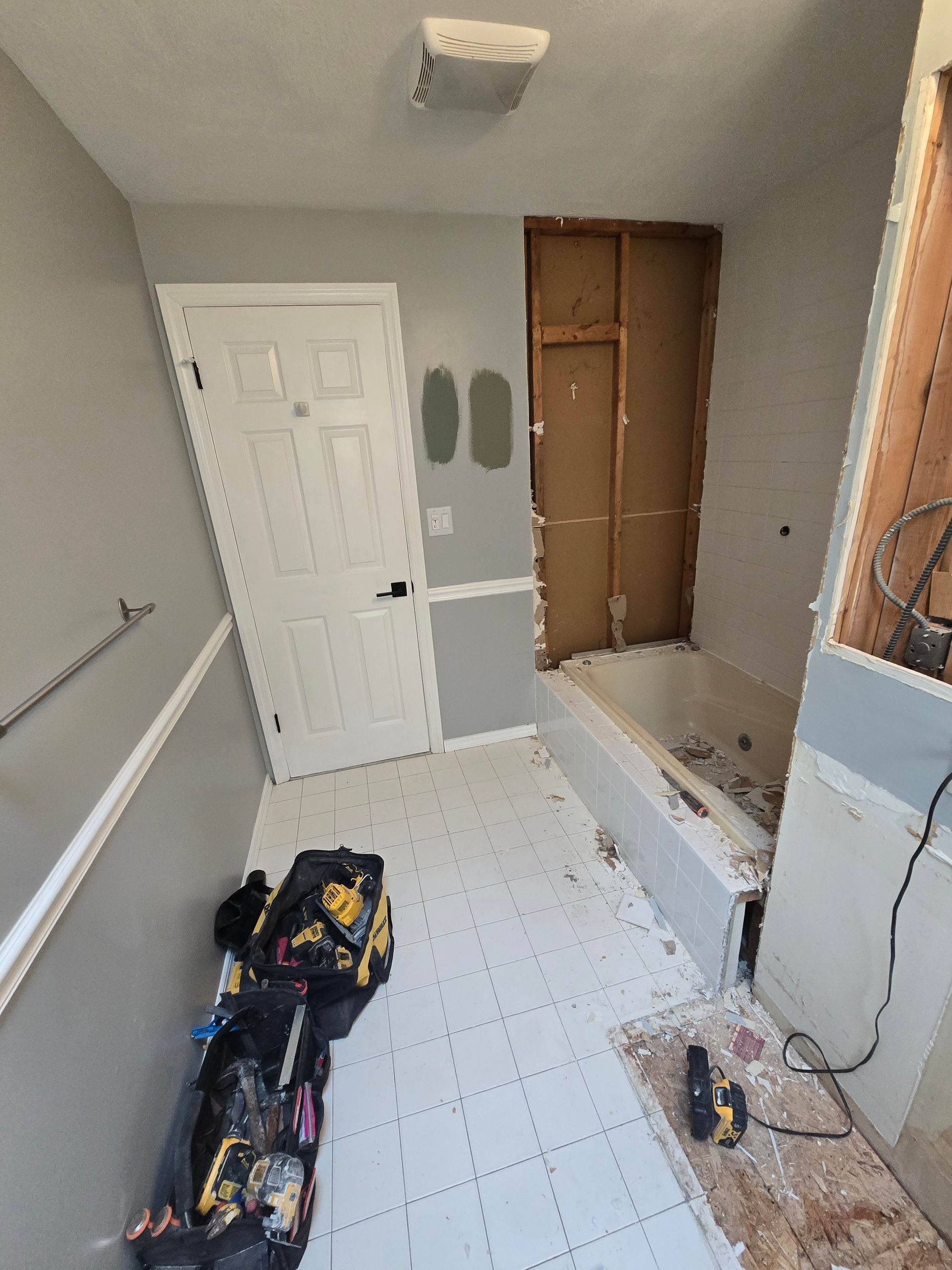 A bathroom with a bathtub and a bag of tools on the floor.