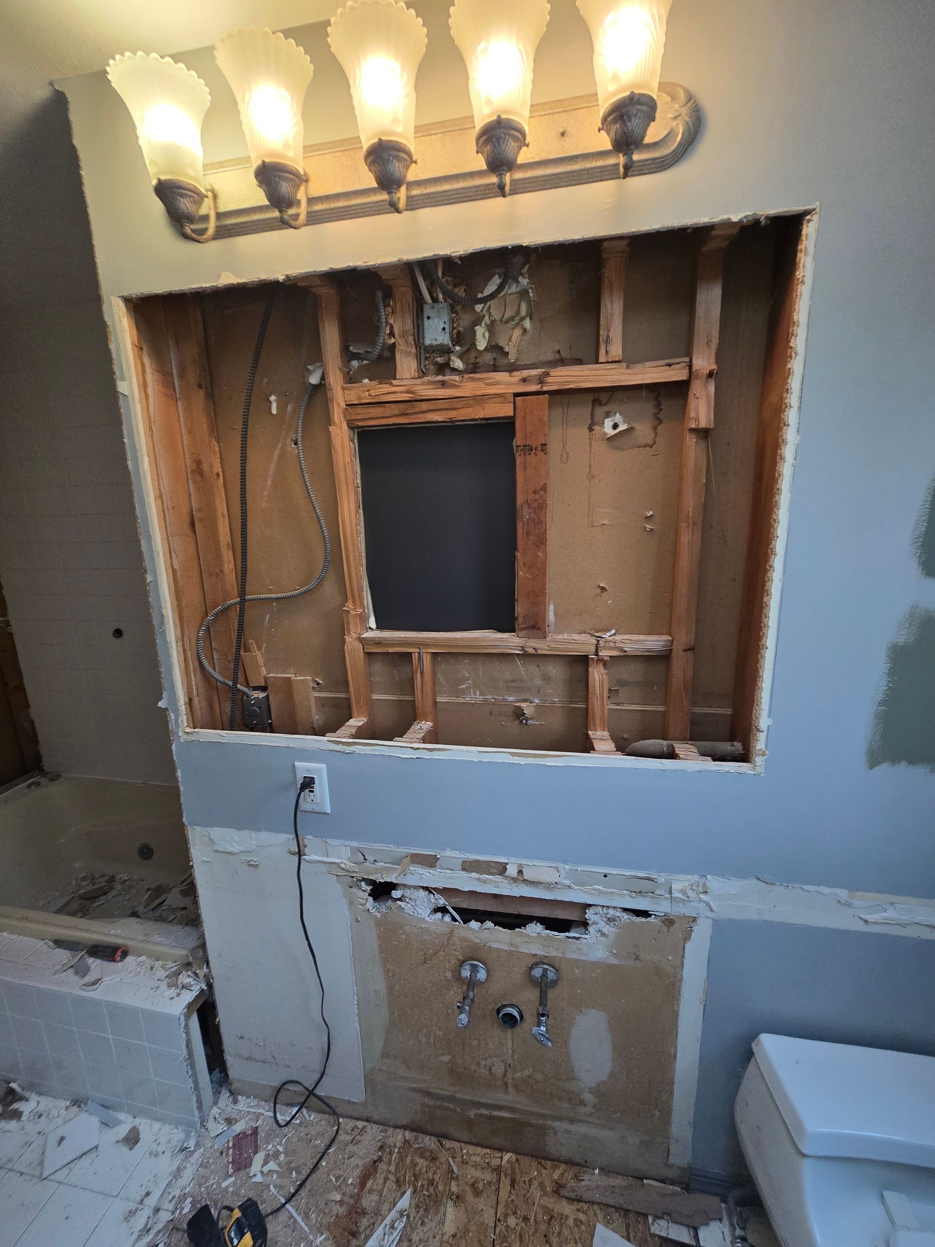 A bathroom vanity is being remodeled with a hole in the wall.