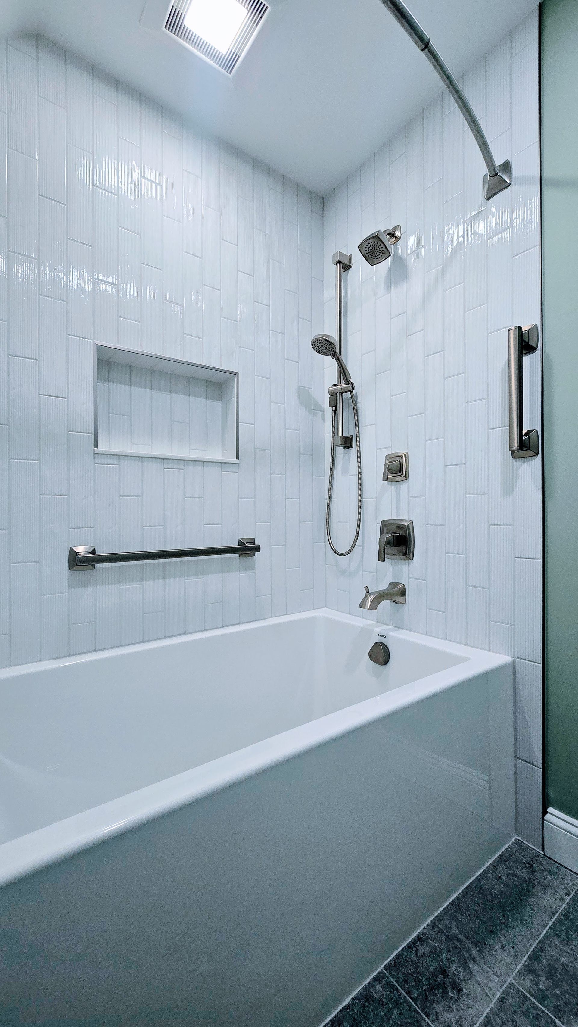 White tiled bathroom in Farmington with tub, shower, and grab bars.
