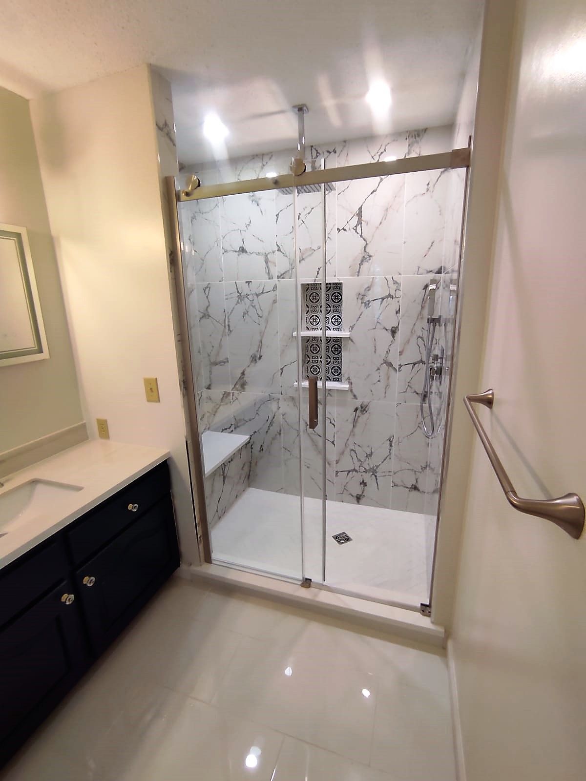 A bathroom with a walk in shower and a sink.