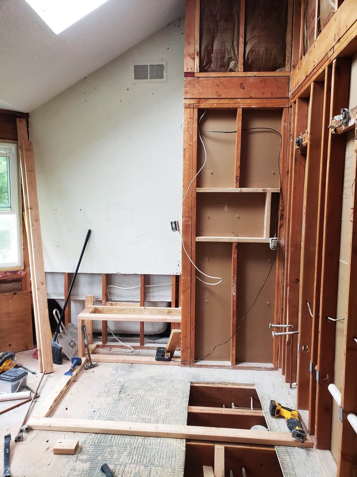 Interior room renovation with exposed studs, drywall, and wooden framing.