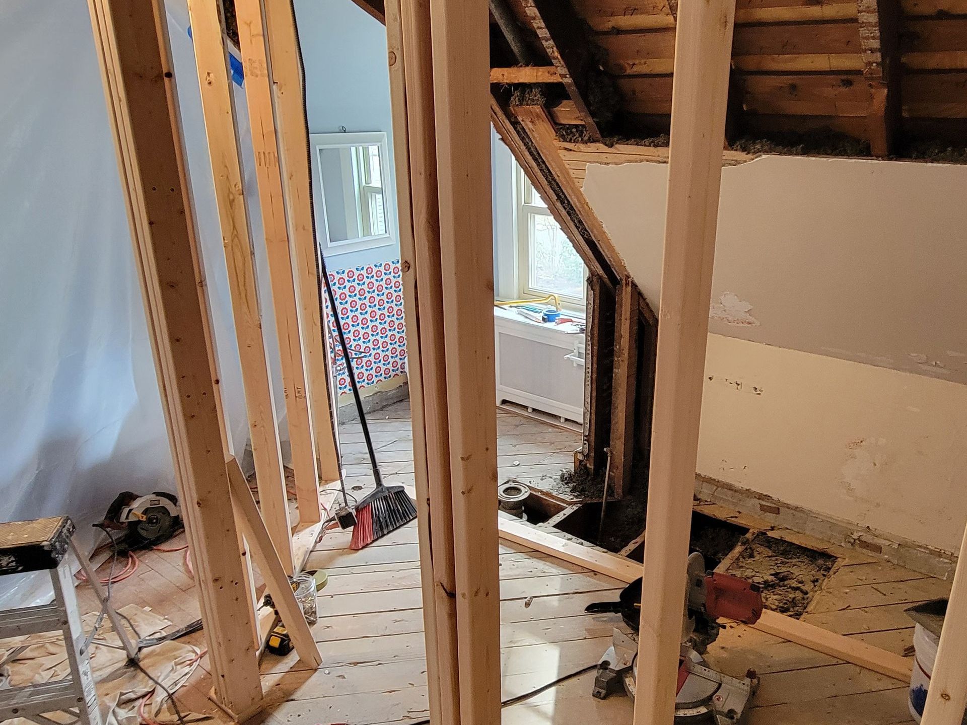 A room under construction with wooden beams and a broom.