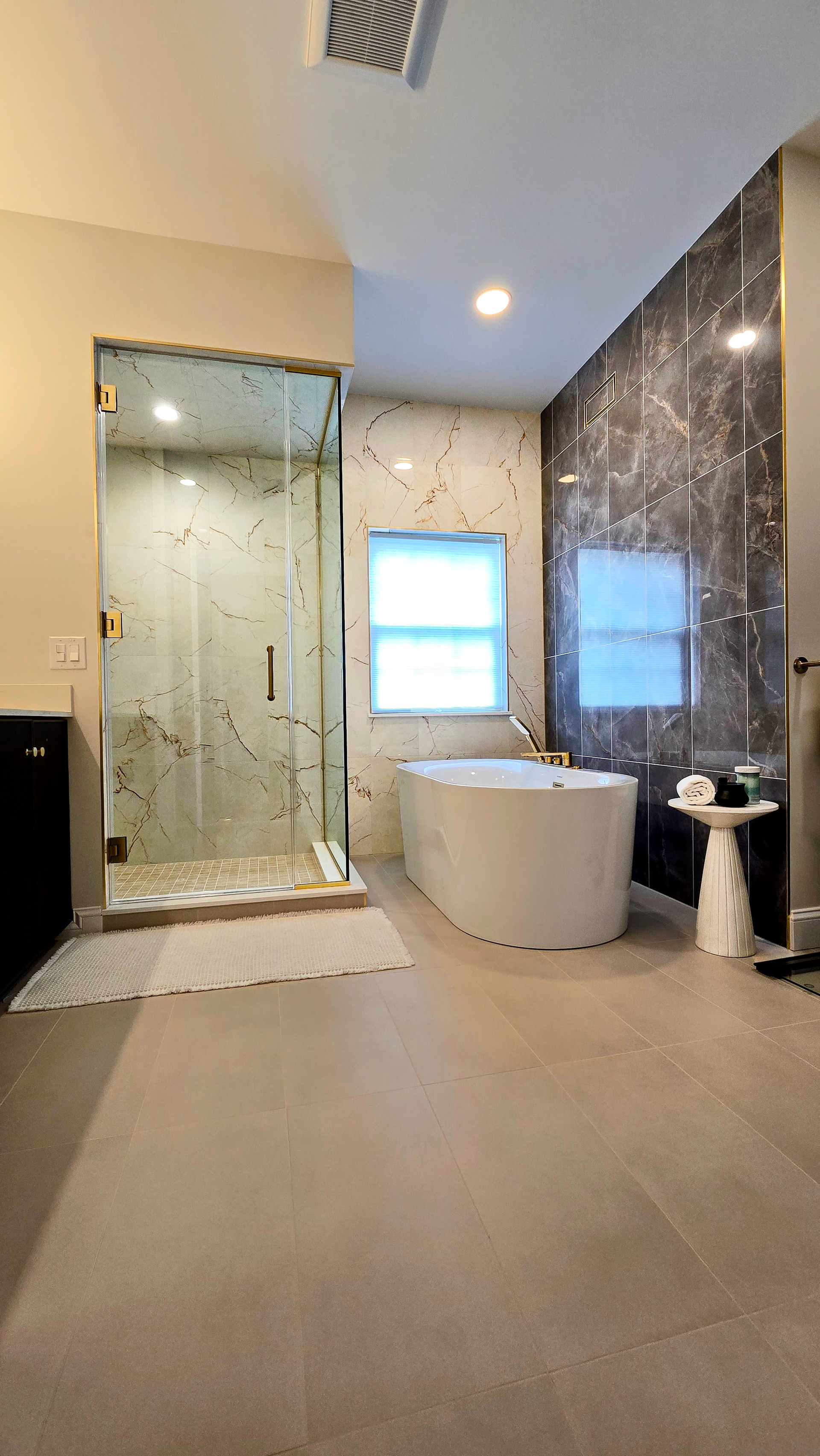 Modern bathroom in Cromwell, CT on the TPC River Highlands Golf Course with glass shower, freestanding tub, and dark marble accent wall