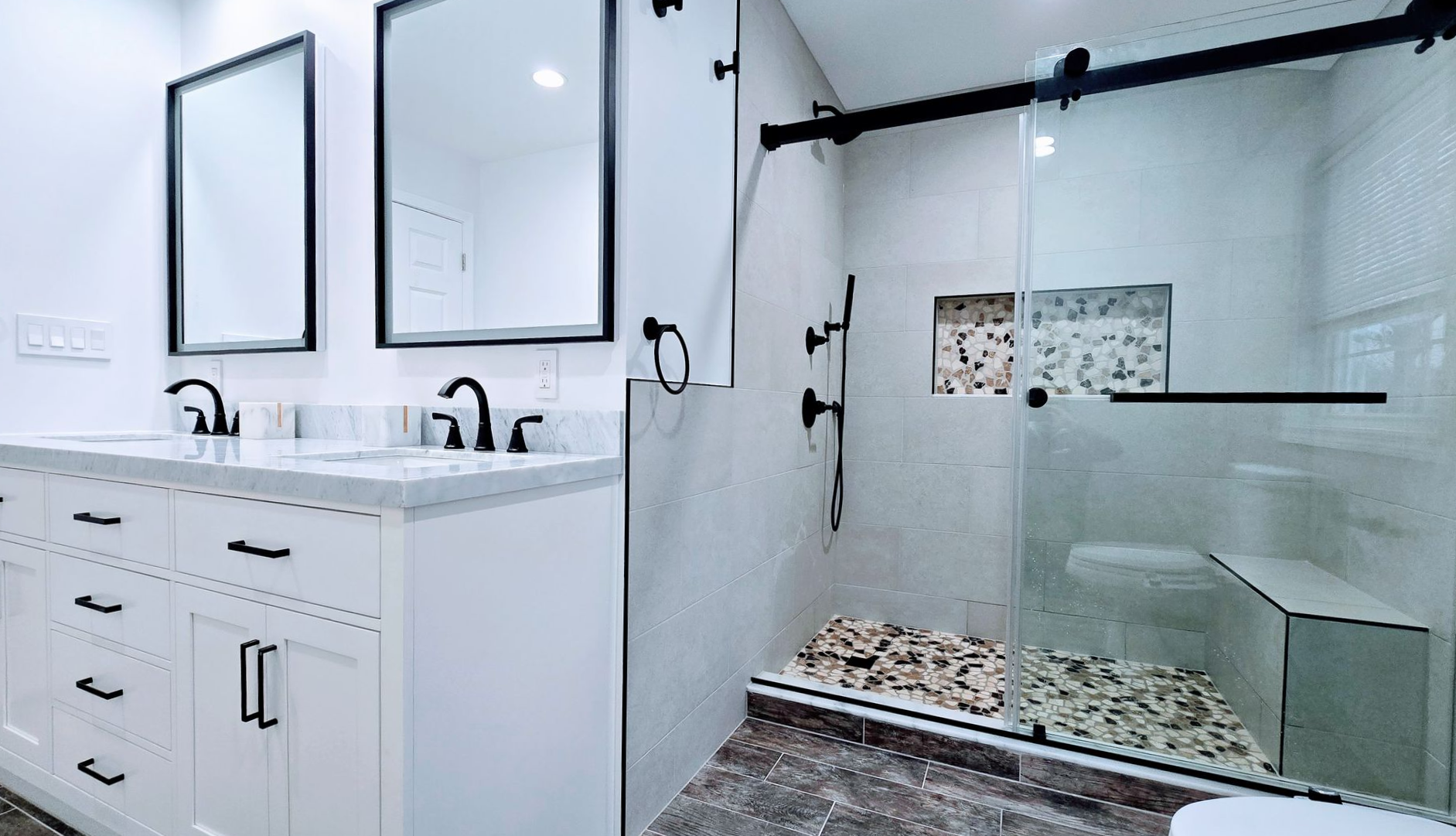 Modern bathroom in Berlin, CTwith white cabinets, dual sinks, black fixtures, and a glass shower.