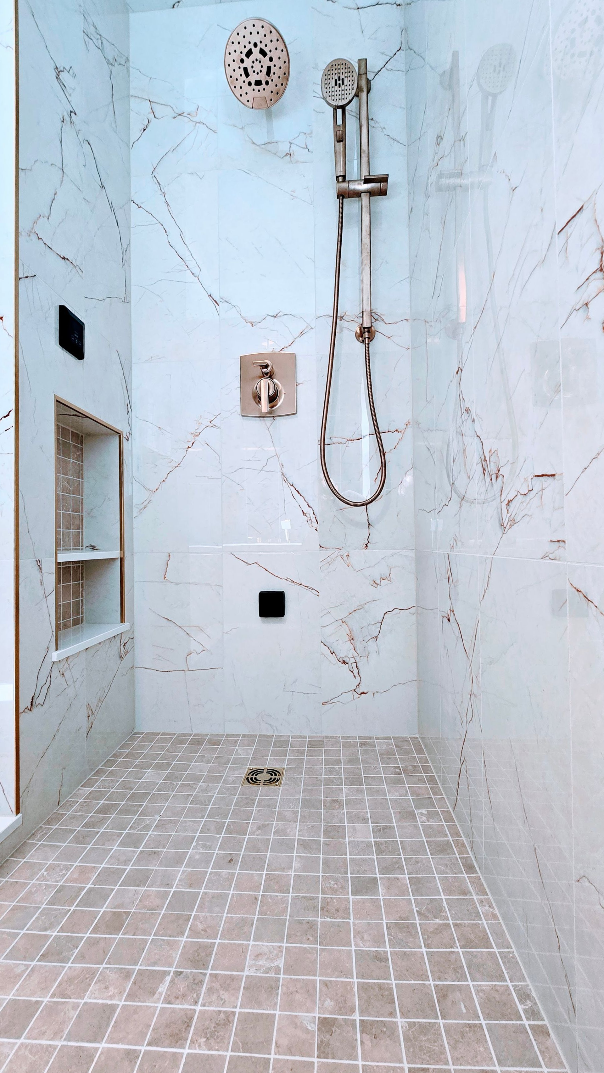 Modern walk-in steam shower in Cromwell, CT on the TPC River Highlands Golf Course with shower area with white tiled walls and floor, mounted showerhead, hose, and drain grate.
