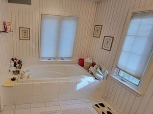 A bathroom with a tub and two windows.