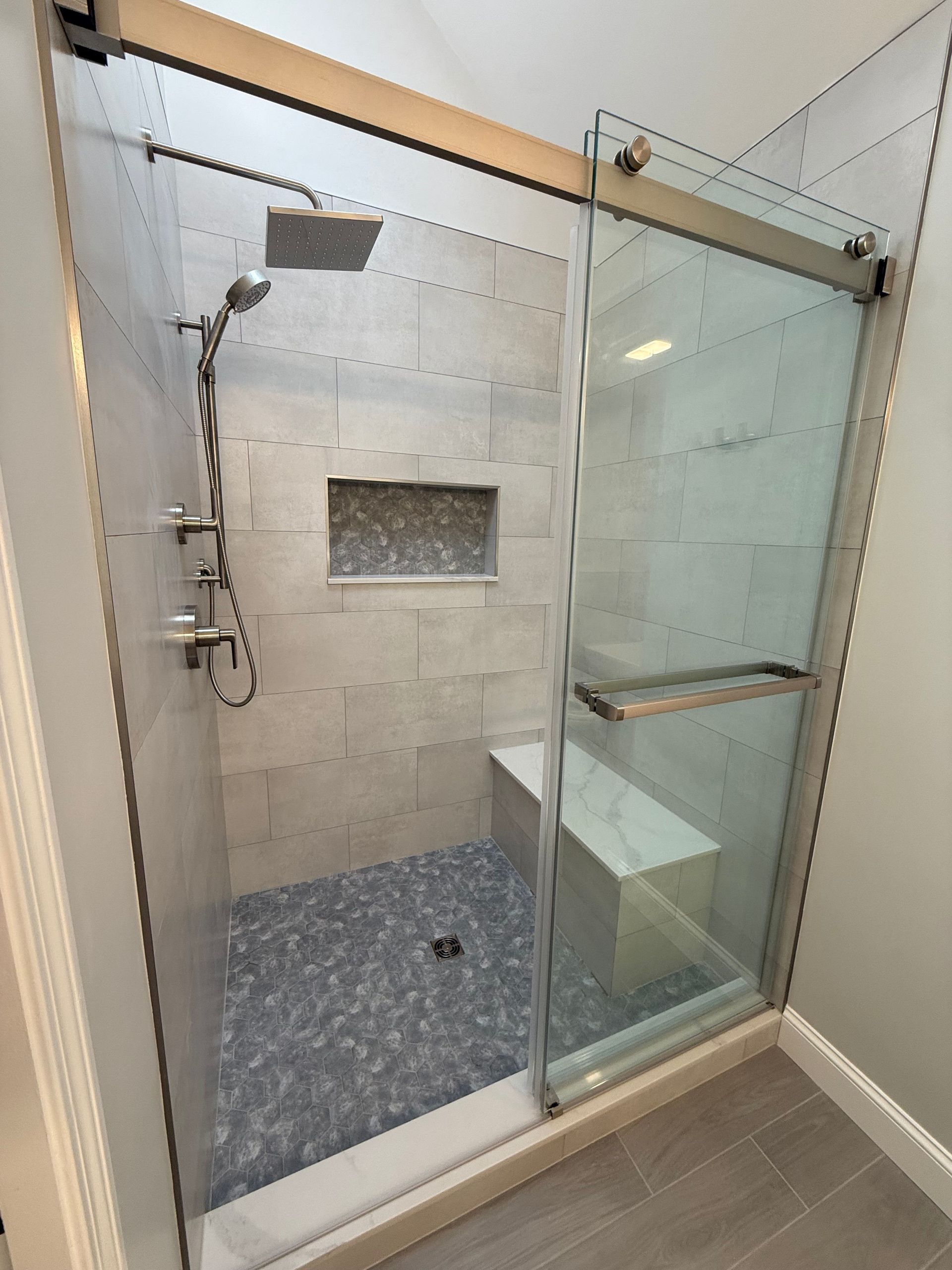 A bathroom with a walk in shower with a sliding glass door.