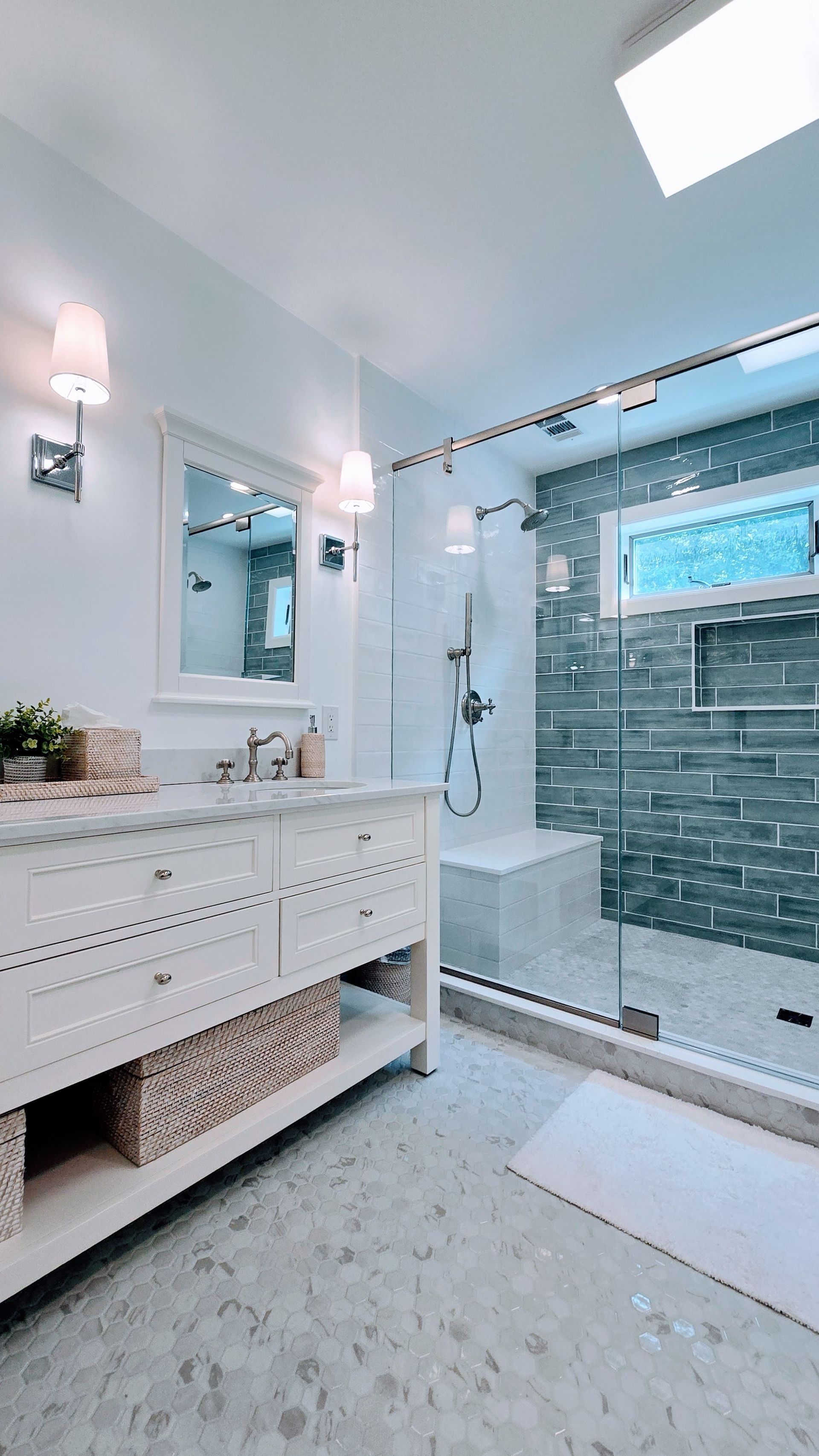 Bright bathroom in Rocky Hill, CT with white vanity, large mirror, glass shower, and gray tile accent wall.