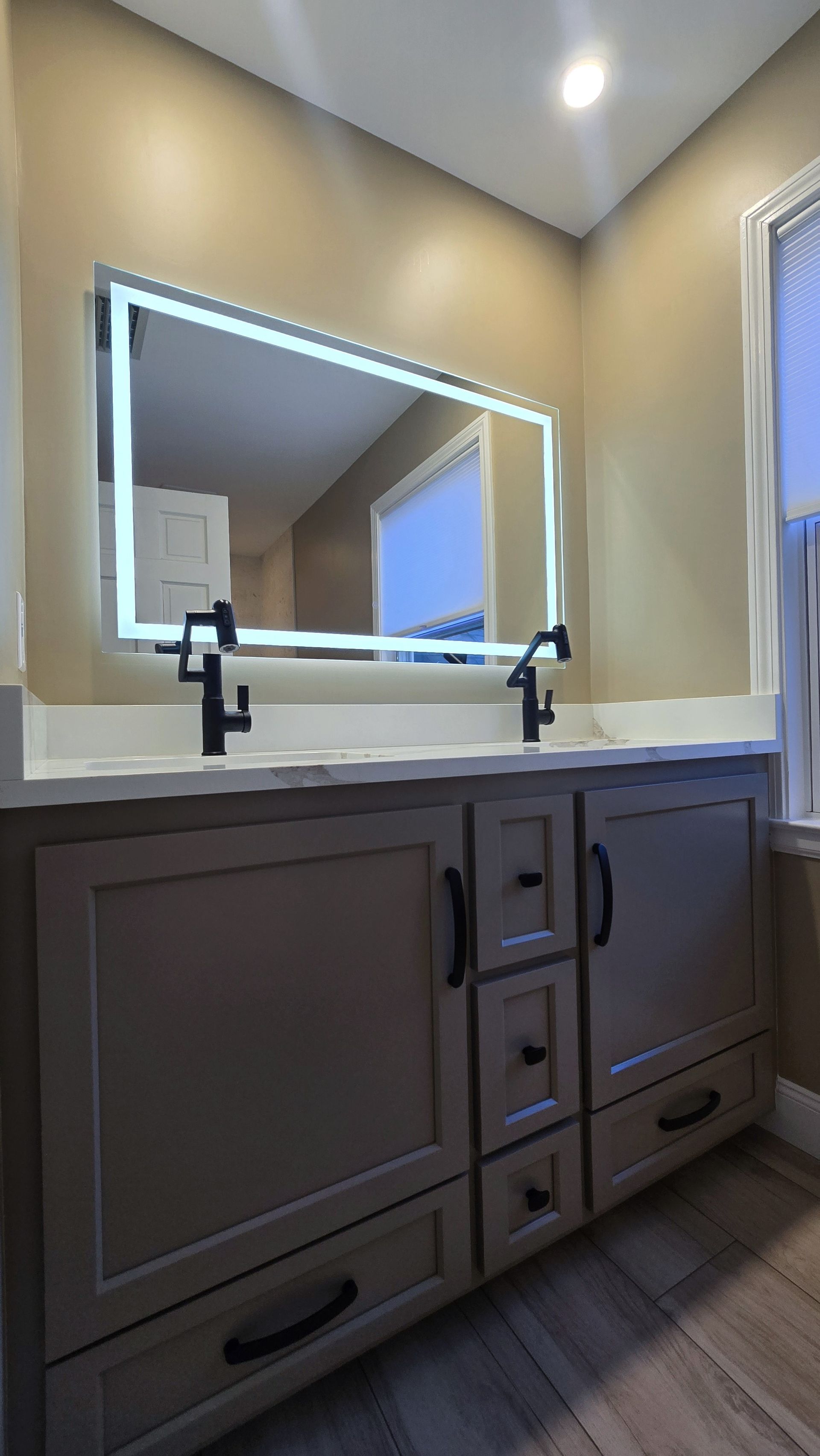 Luxurious bathroom remodel in Wolcott, CT with dark green vanity, white tub, gold fixtures, and arched mirror.