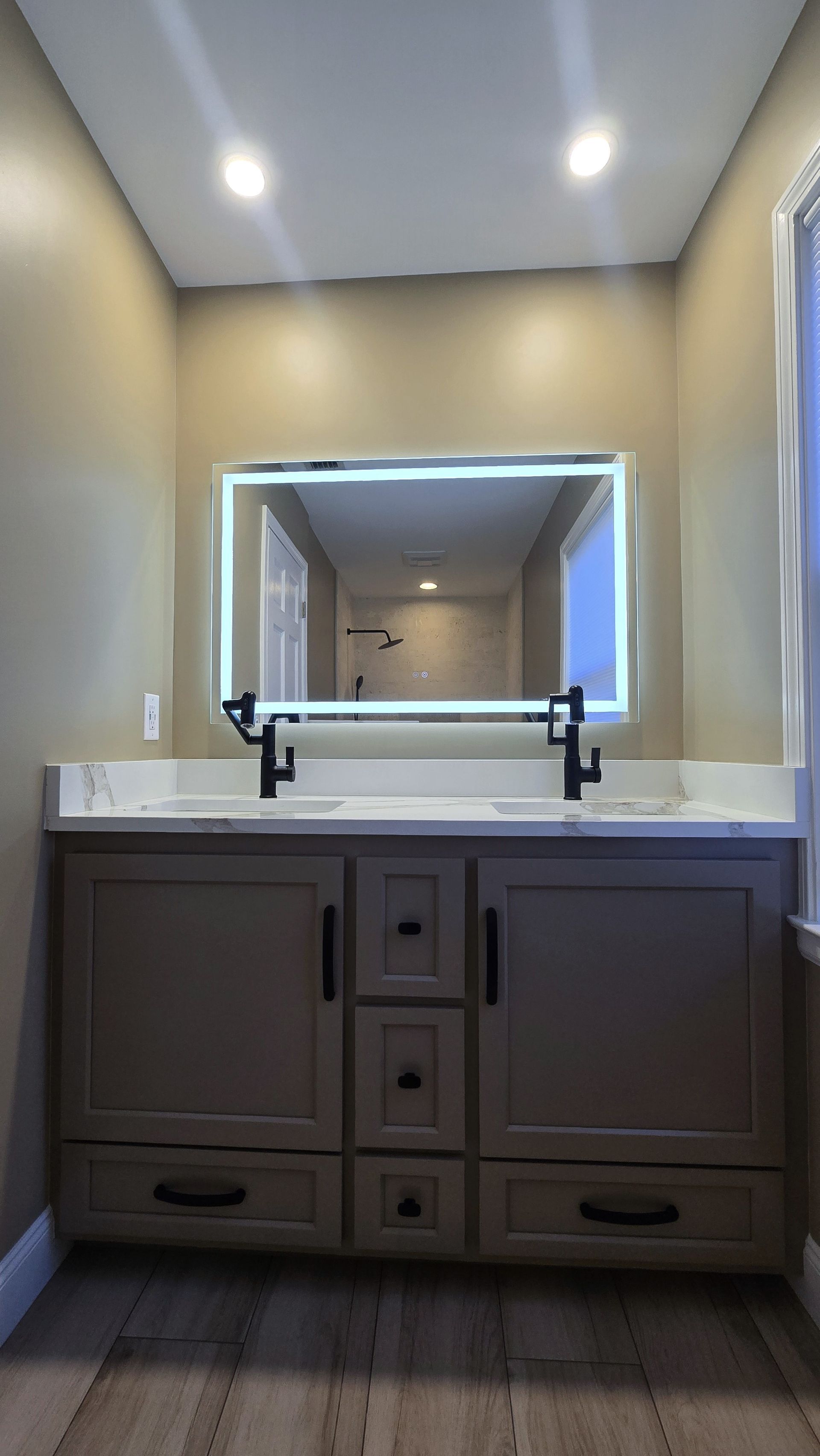 Bristol bathroom vanity with black fixtures, lit mirror, and neutral walls.