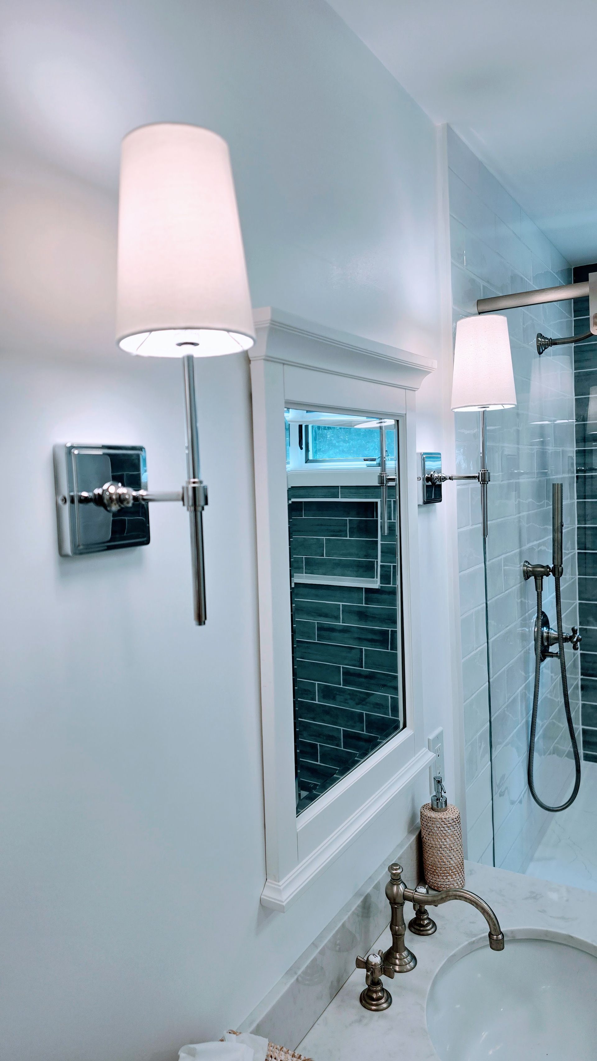 Bathroom vanity in Rocky Hill, CT with wall sconce, mirror, and shower stall in a bright modern bathroom