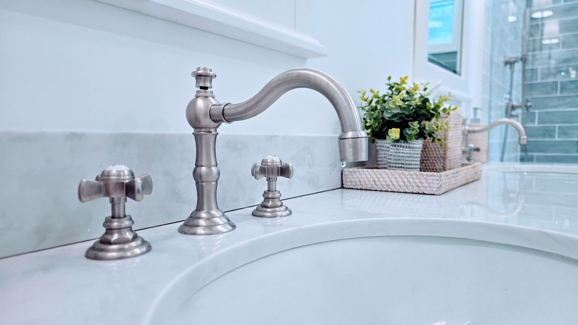 Polished chrome bathroom sink faucet in Rocky Hill, CT with curved spout and matching handles beside a white basin