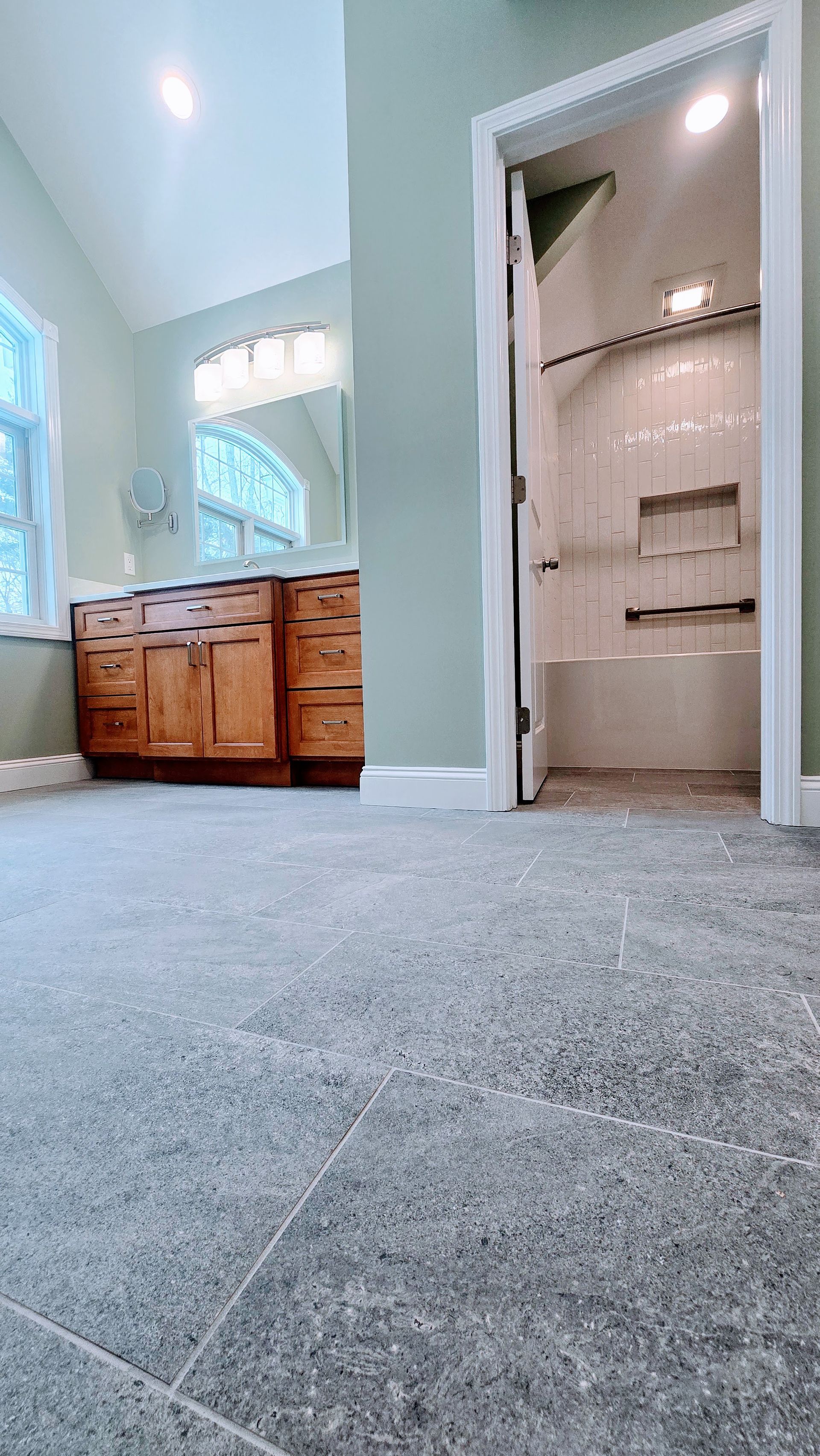 Bathroom in Glastonbury, CT with stone tile floor, wood vanity, and a shower with built-in shelves.