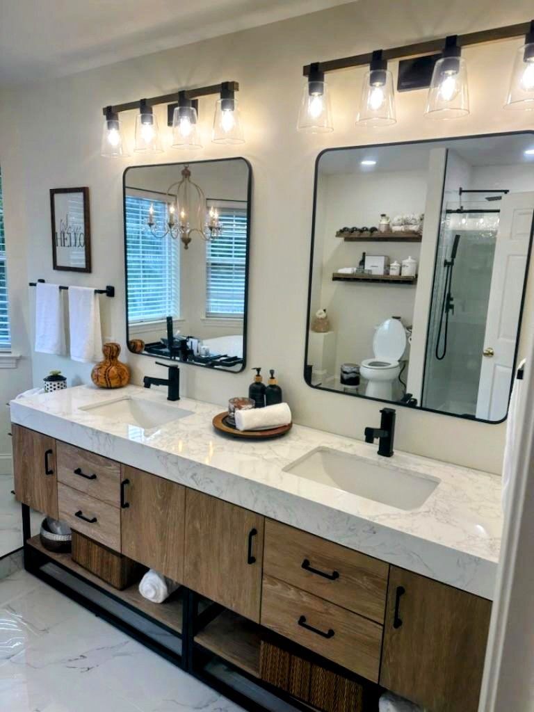 Bathroom with double vanity featuring wood cabinets, white countertop, black fixtures, and large mirrors.