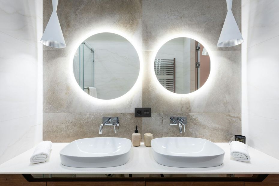 Bathroom in Avon, CT with two round mirrors, vessel sinks, and modern lighting.