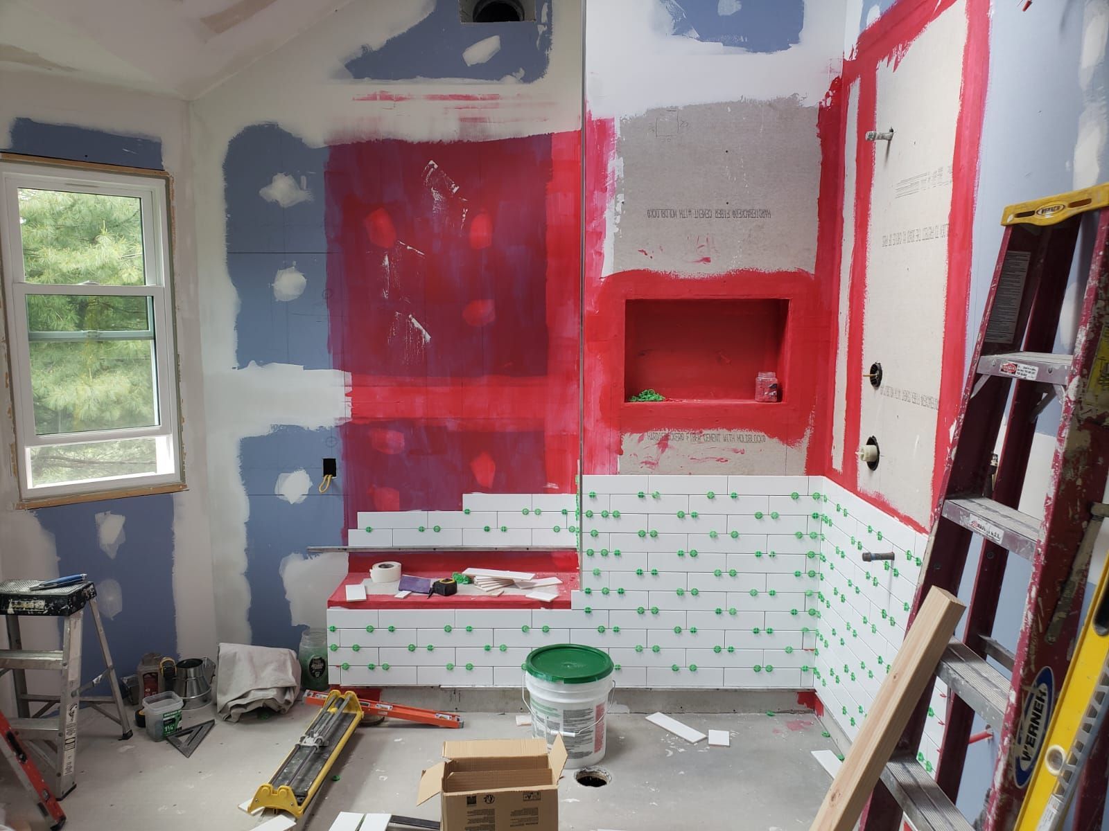 A bathroom that is being remodeled with a red wall