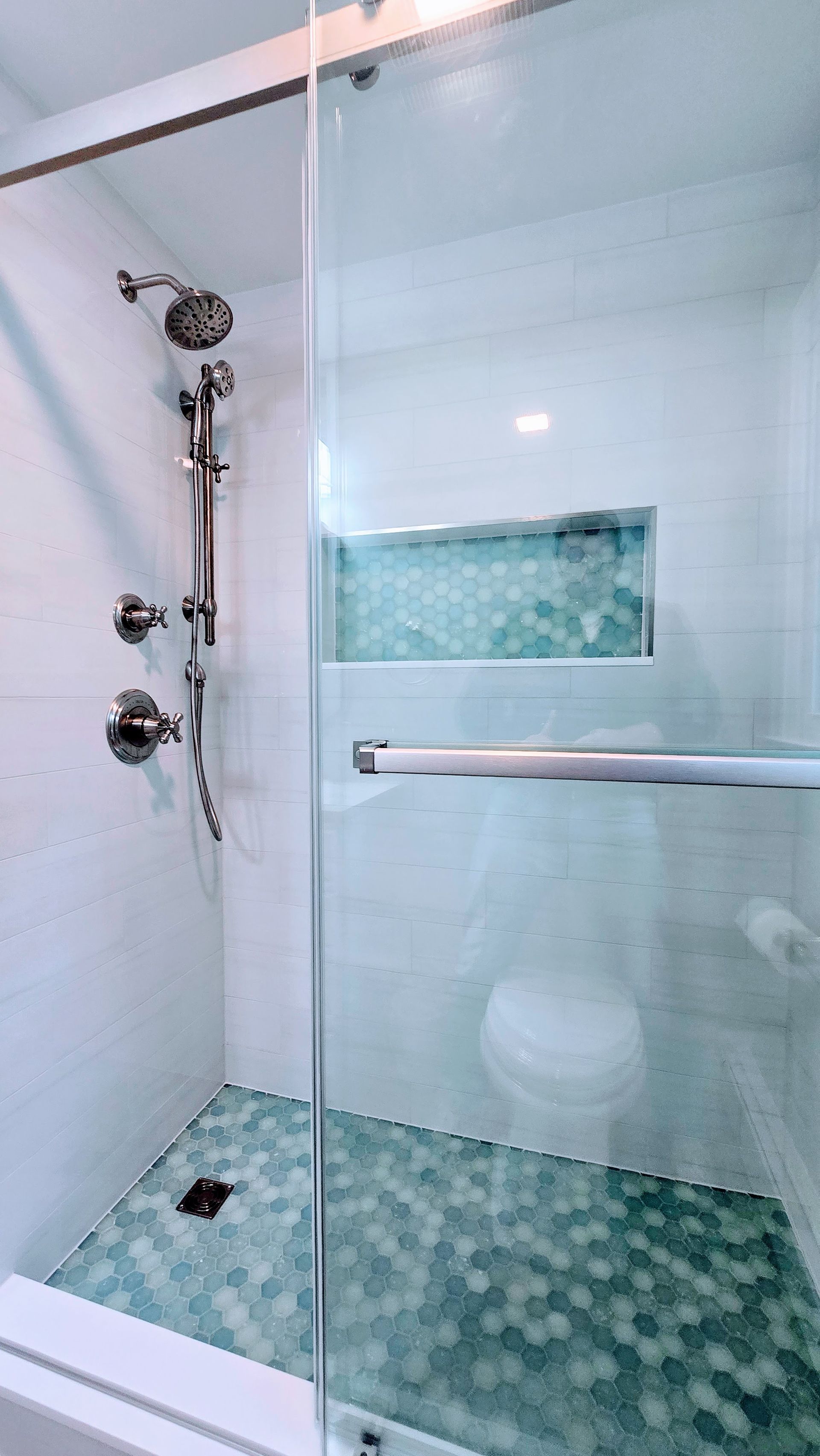 Walk-in Shower in Farmington, CT with glass door, silver fixtures, and turquoise hexagonal tile floor.