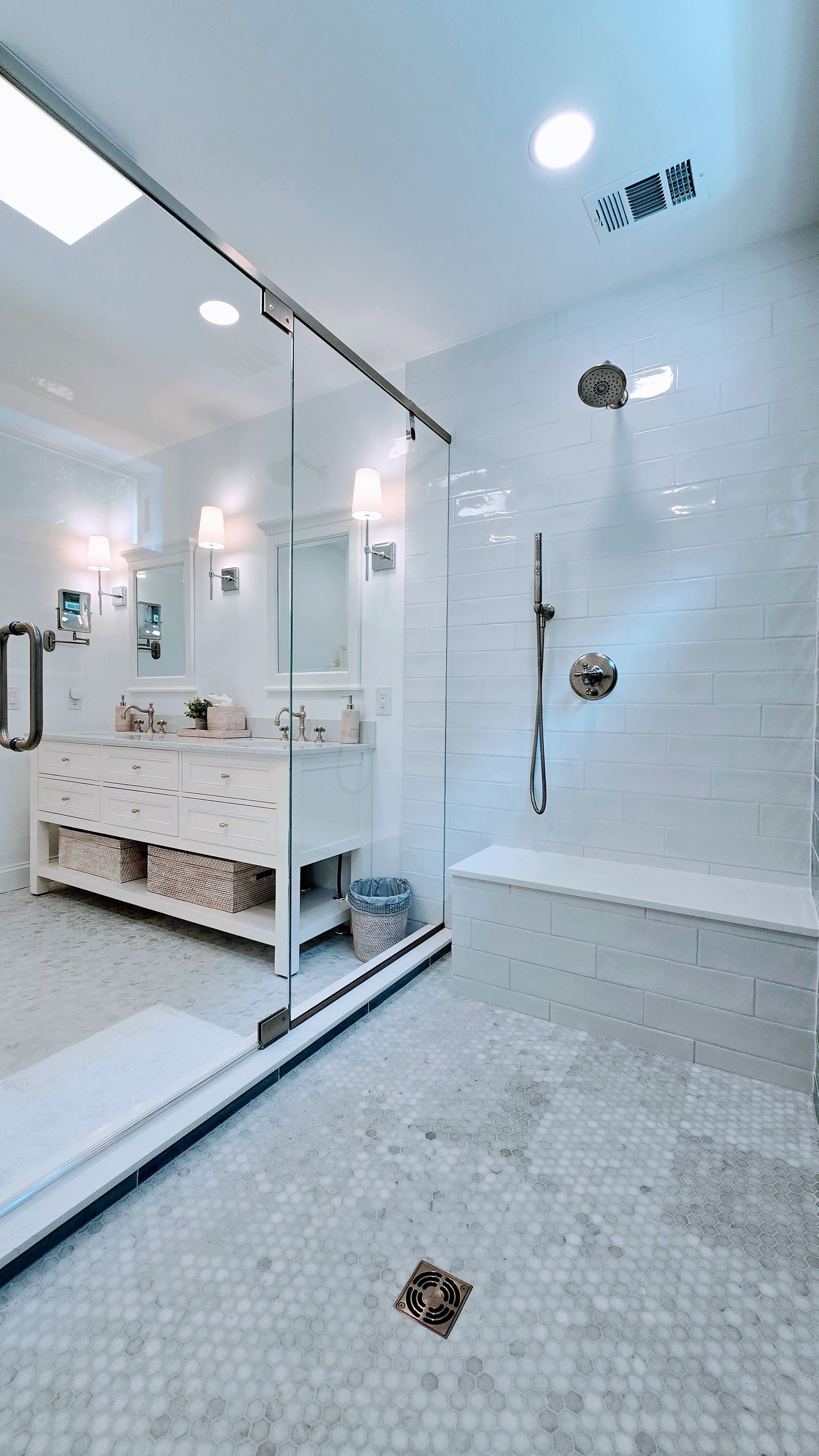Bright modern bathroom in Rocky Hill, CT with glass shower, vanity, and white tiled walls and floor.