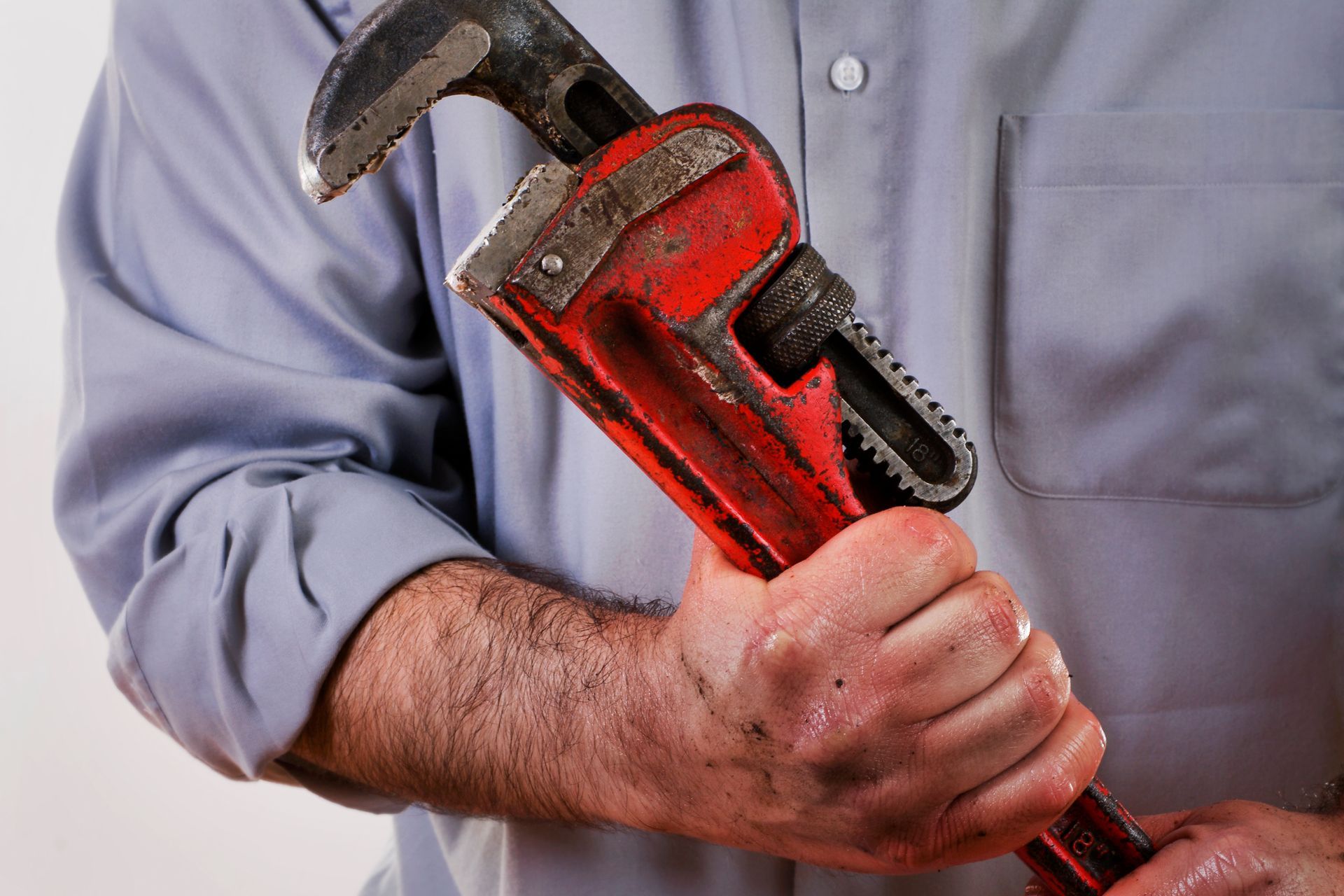 Man trying to fix a leak in a sink using a pipe wrench.