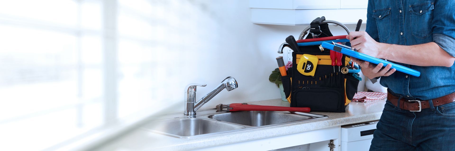 Residential plumbing contractor inspecting kitchen sink plumbing.