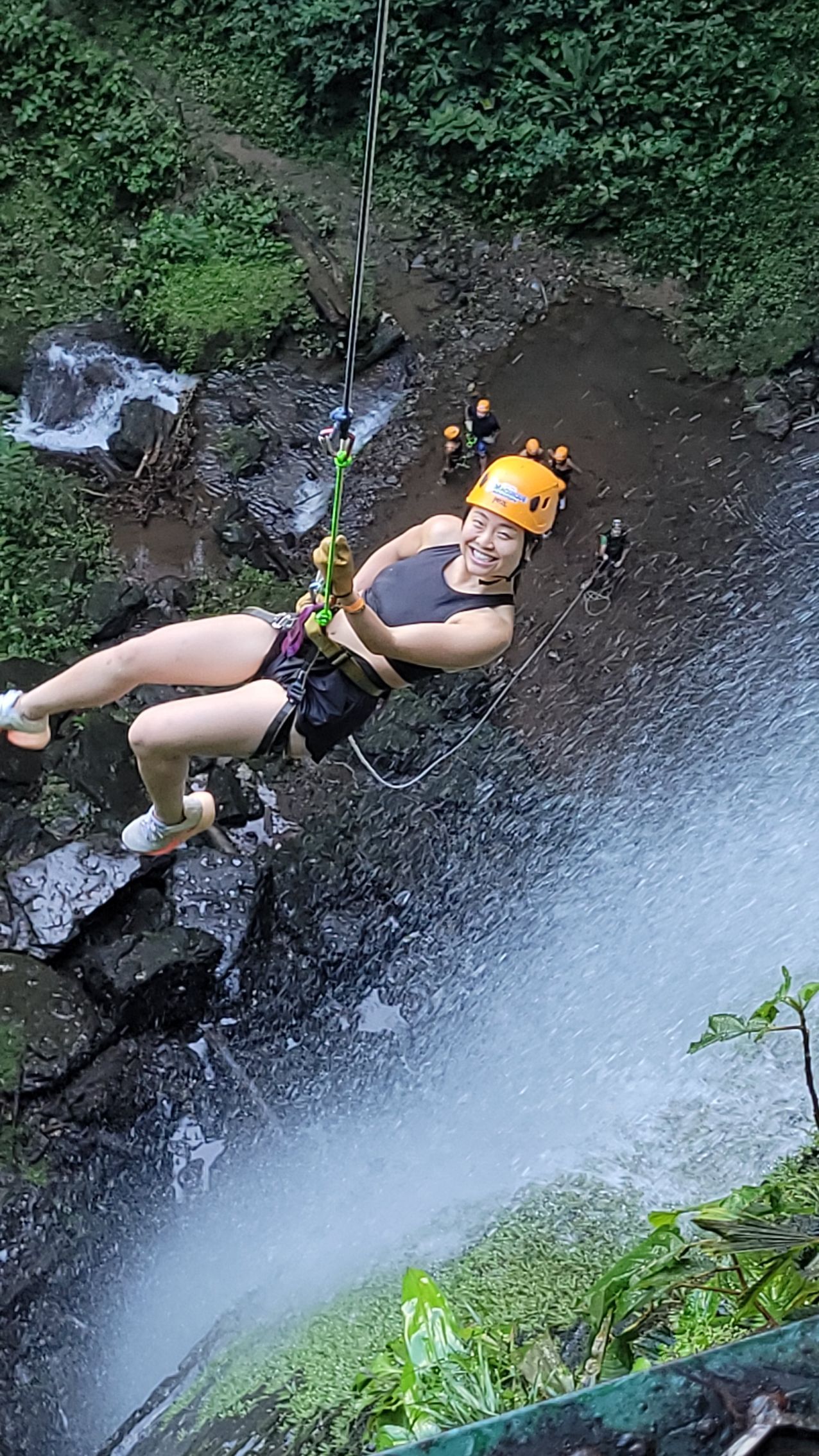 a woman is hanging from a rope over a waterfall .