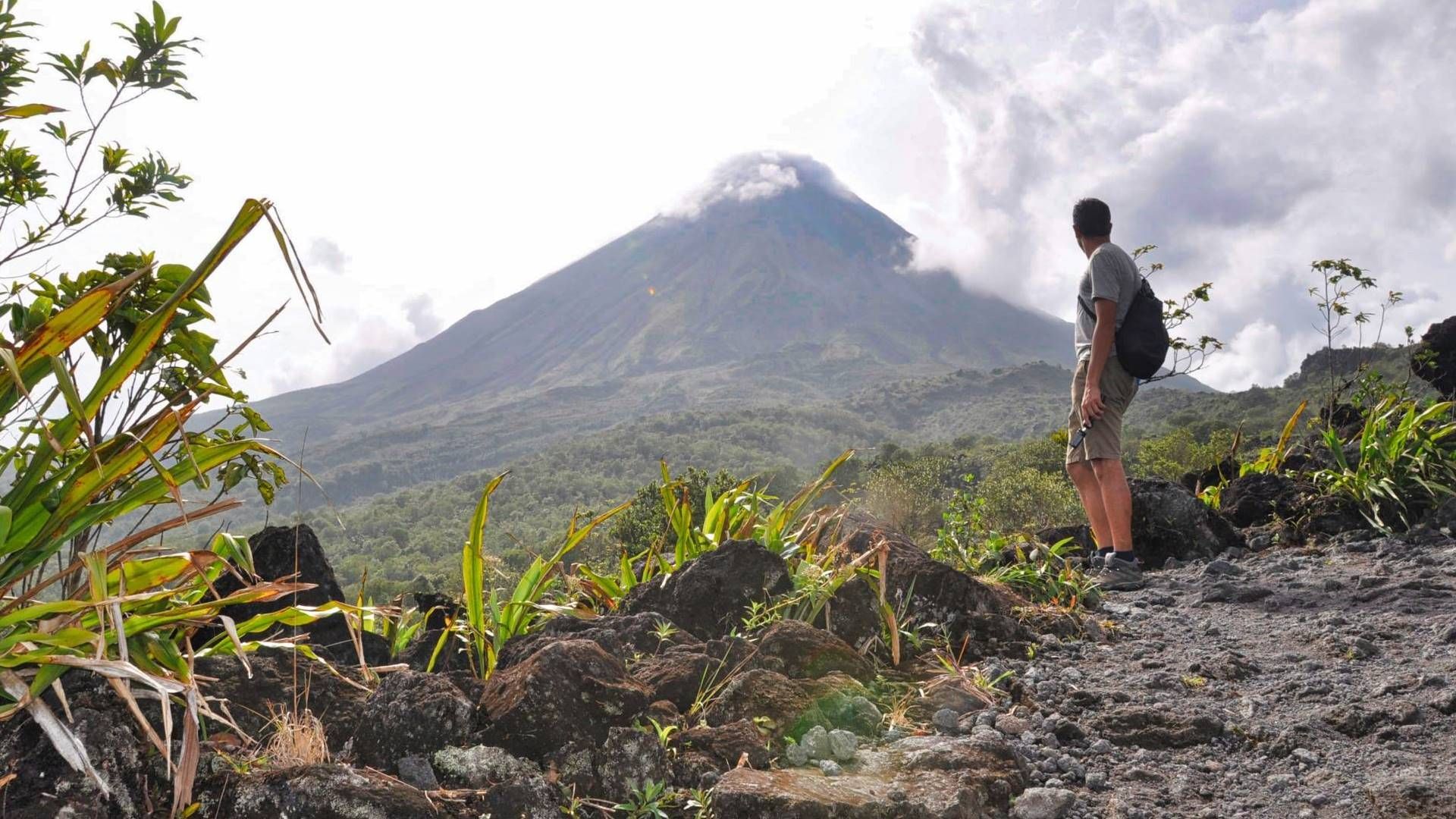 a man with a backpack is standing in front of a mountain