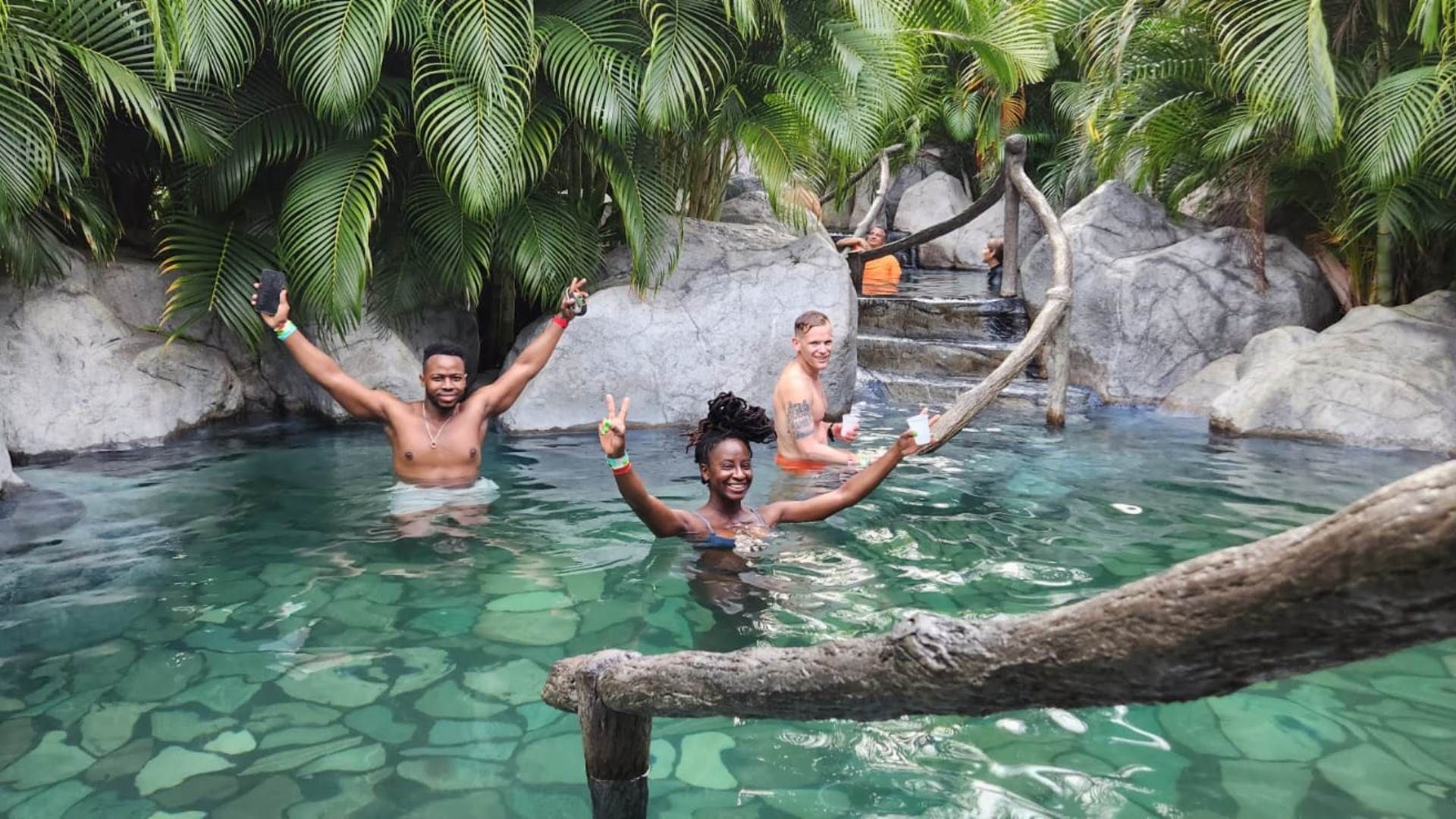a group of people are swimming in a pool with their arms in the air .