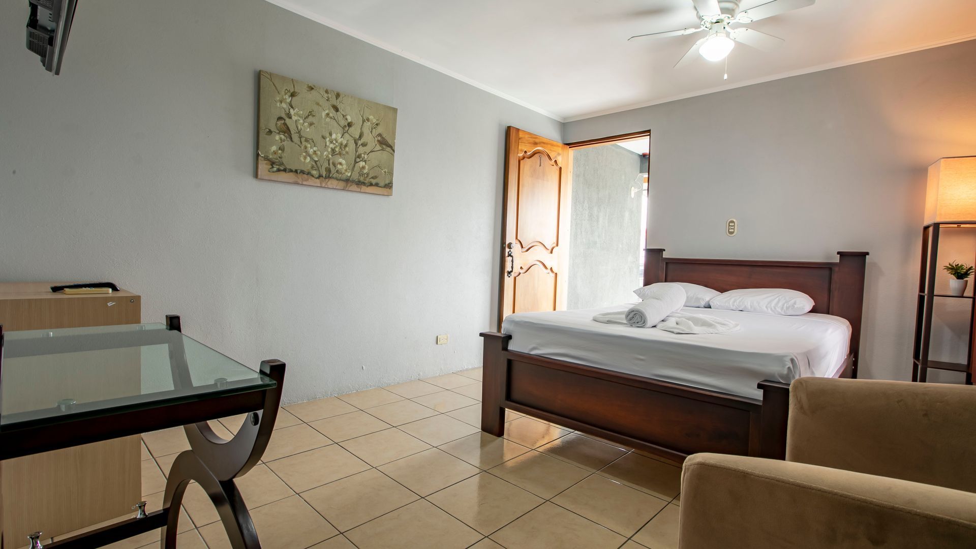 a bedroom with a bed , chair , desk and ceiling fan .