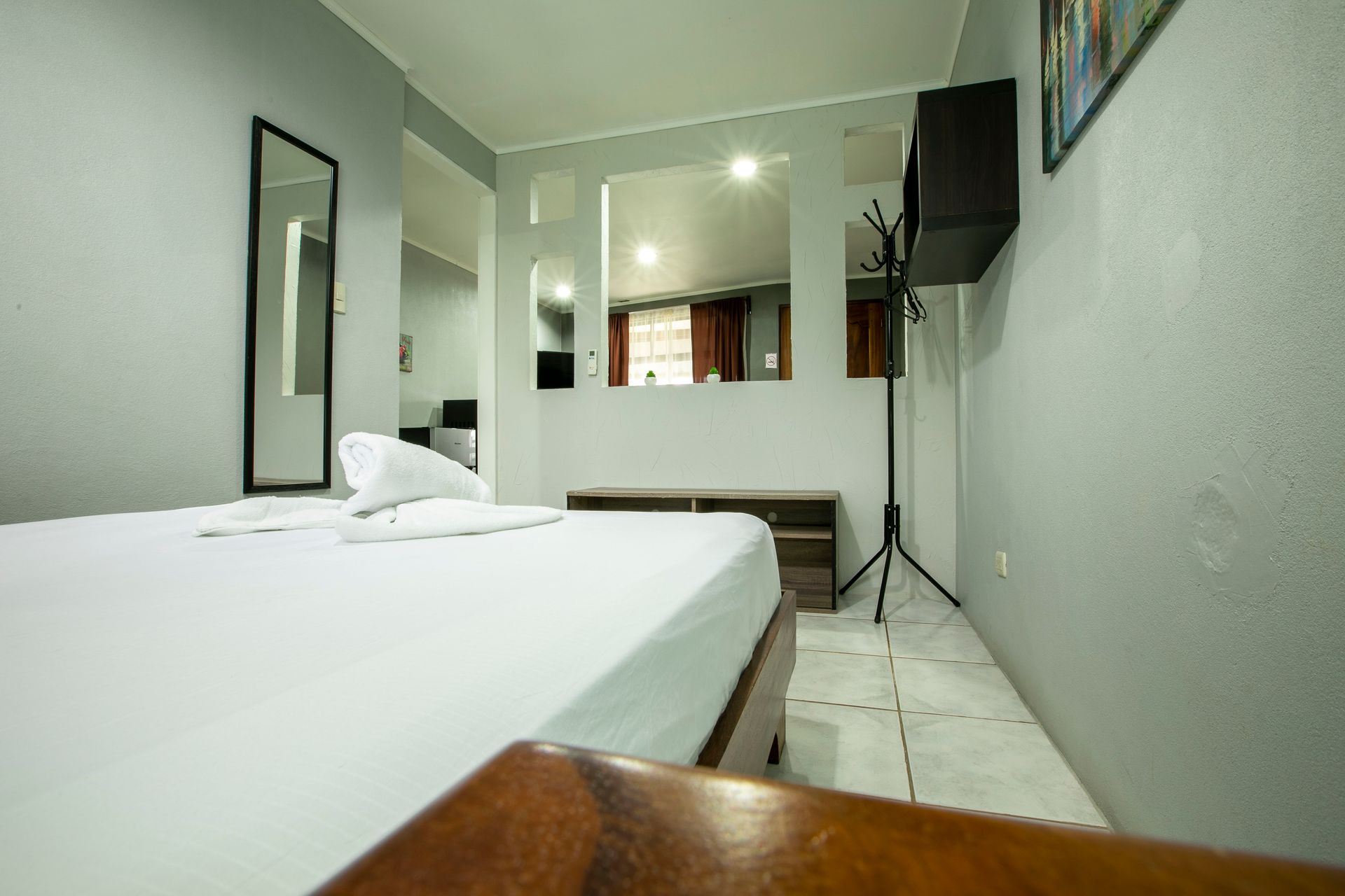 a bedroom with a bed , mirror , and a wooden table .