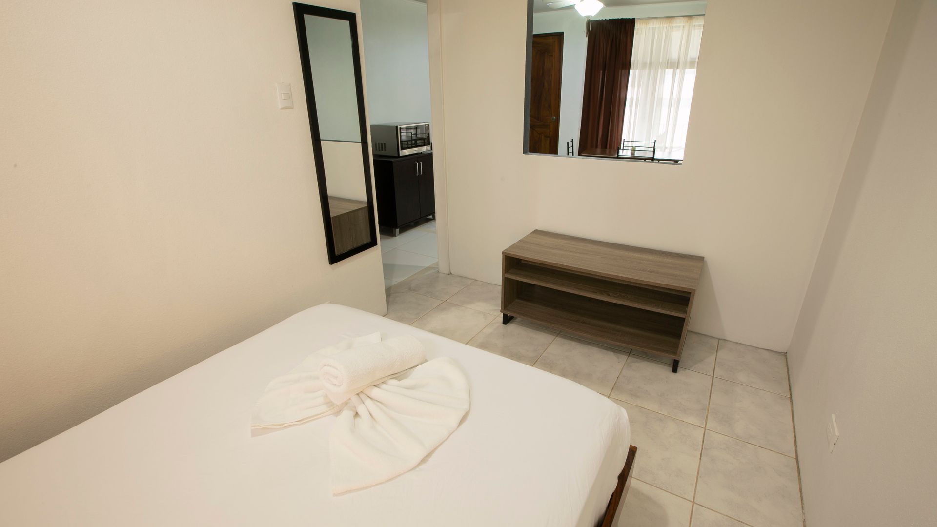 a bedroom with a bed , mirror and bench .