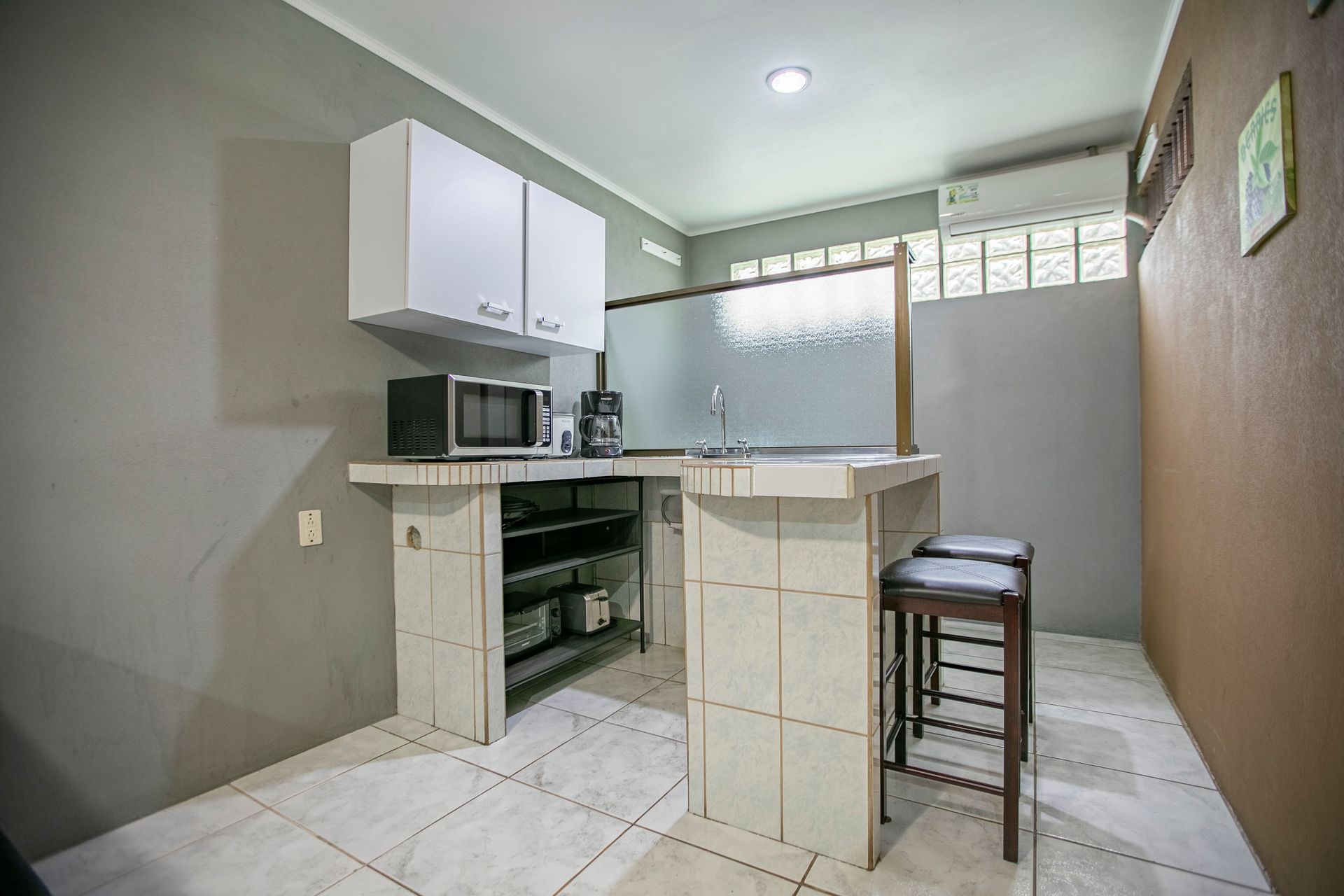 a kitchen with a microwave , sink , and stools .
