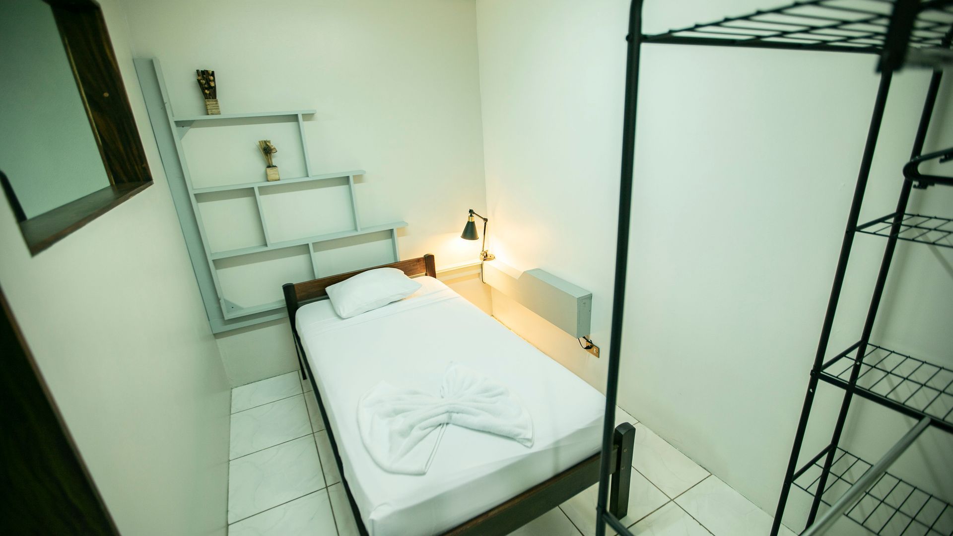 a small bedroom with a single bed and a mirror .