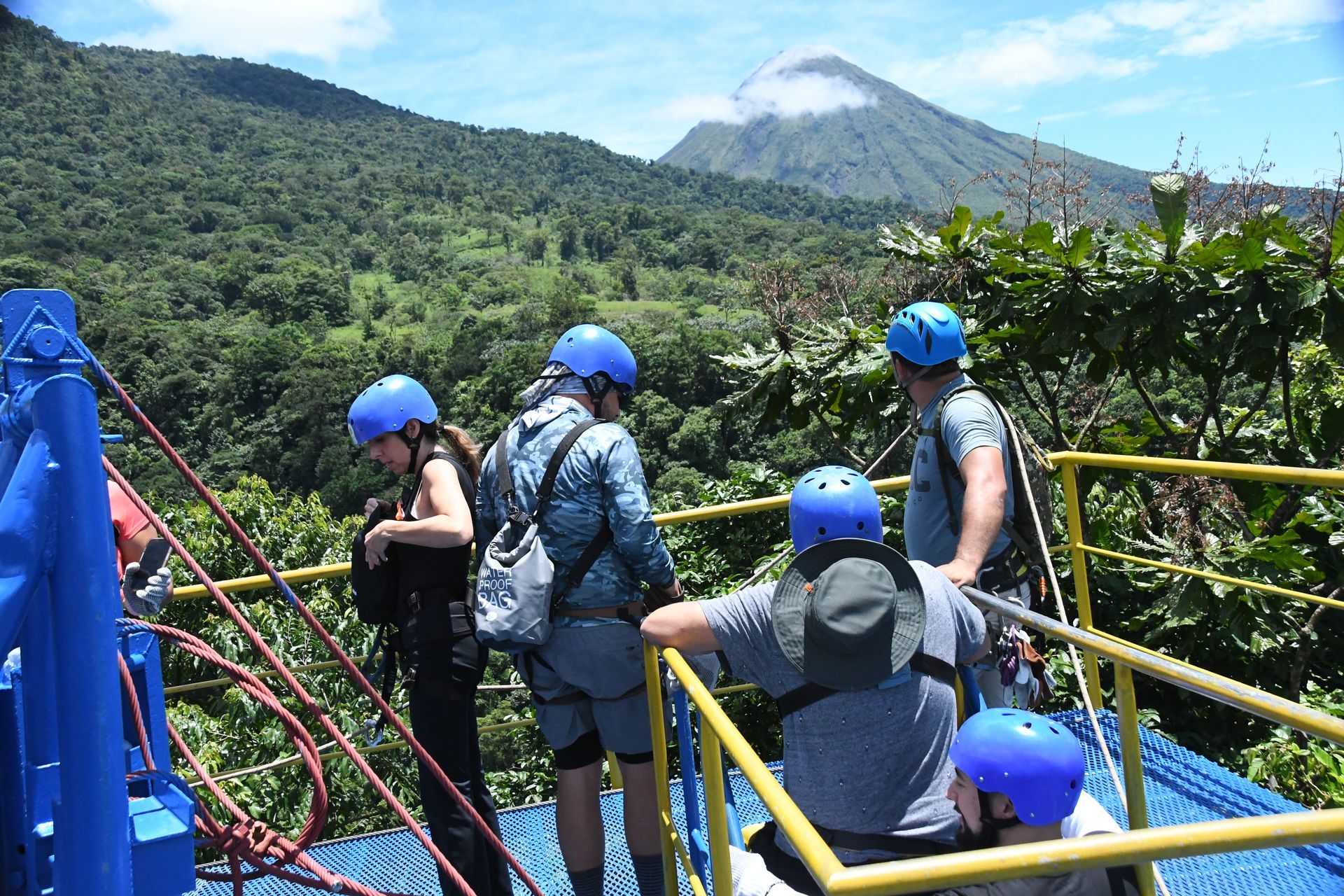a group of people are standing on a bridge looking at a mountain .