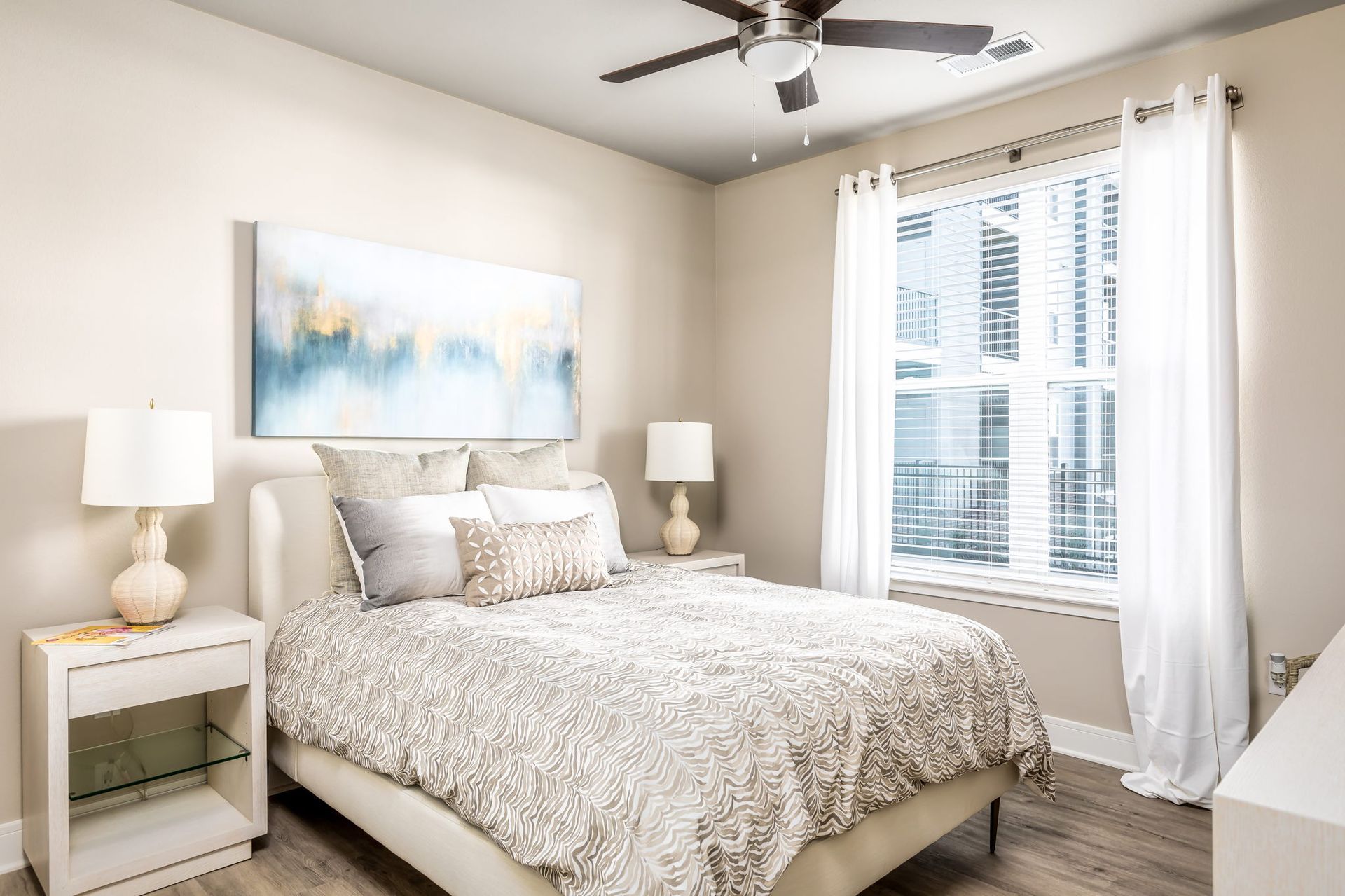 A bedroom with a bed , nightstand , lamps and a ceiling fan.