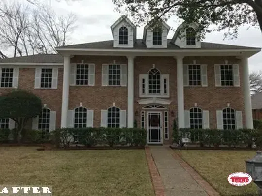 A large brick house with white shutters and columns