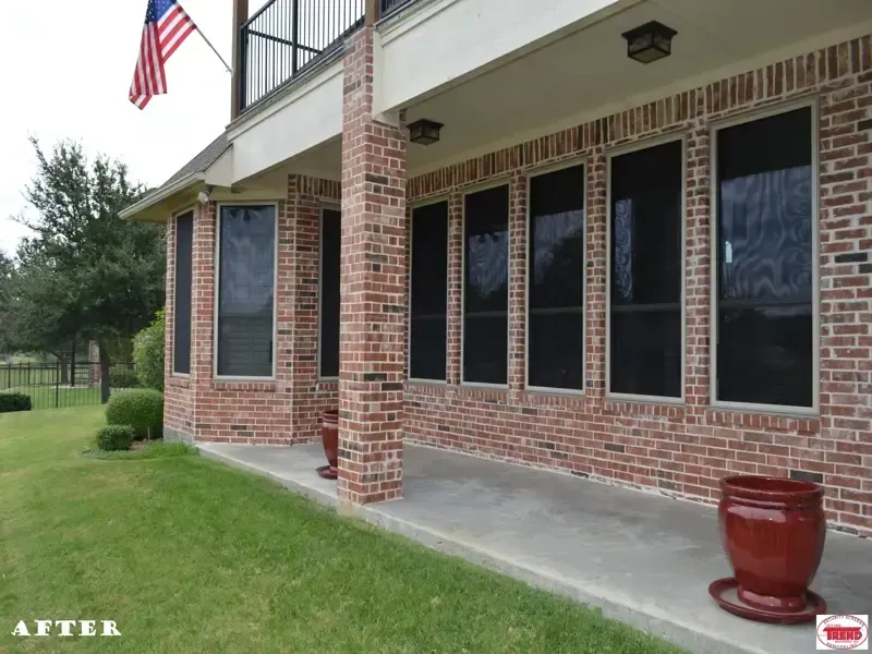 A brick house with black screens on the windows