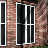 There are two windows on the side of a brick building.