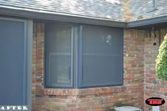A picture of a brick house with a black window.