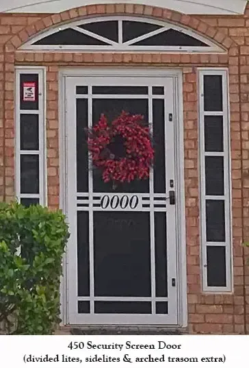A security screen door with a wreath on it is on a brick building.