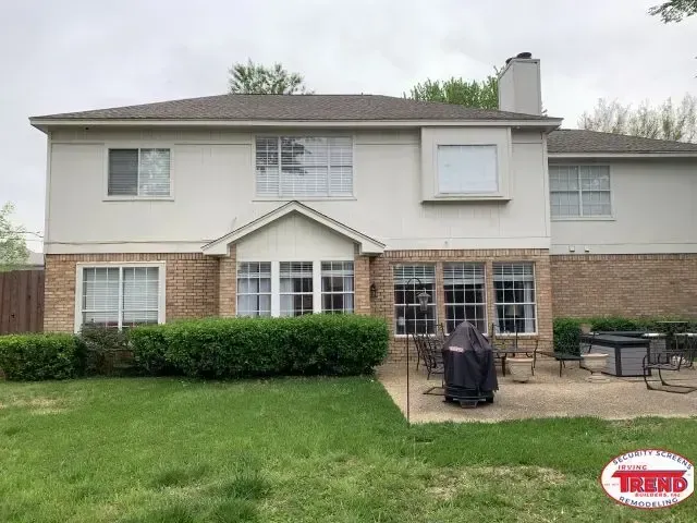 A large house with a lot of windows and a patio in front of it.