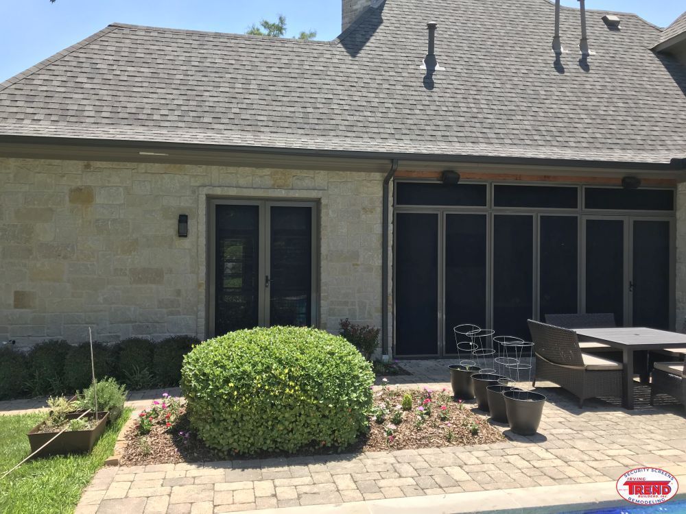 A house with a screened in porch and a table and chairs in front of it.