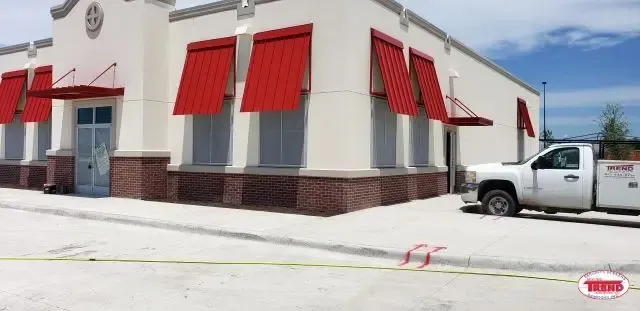 A white truck is parked in front of a building with red awnings.